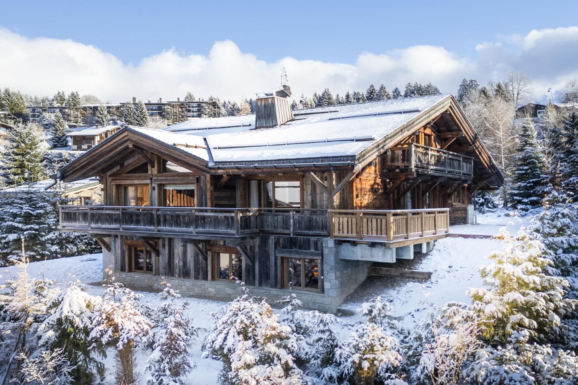 Timber chalet exterior featuring wrap-around balconies and stone-clad lower level