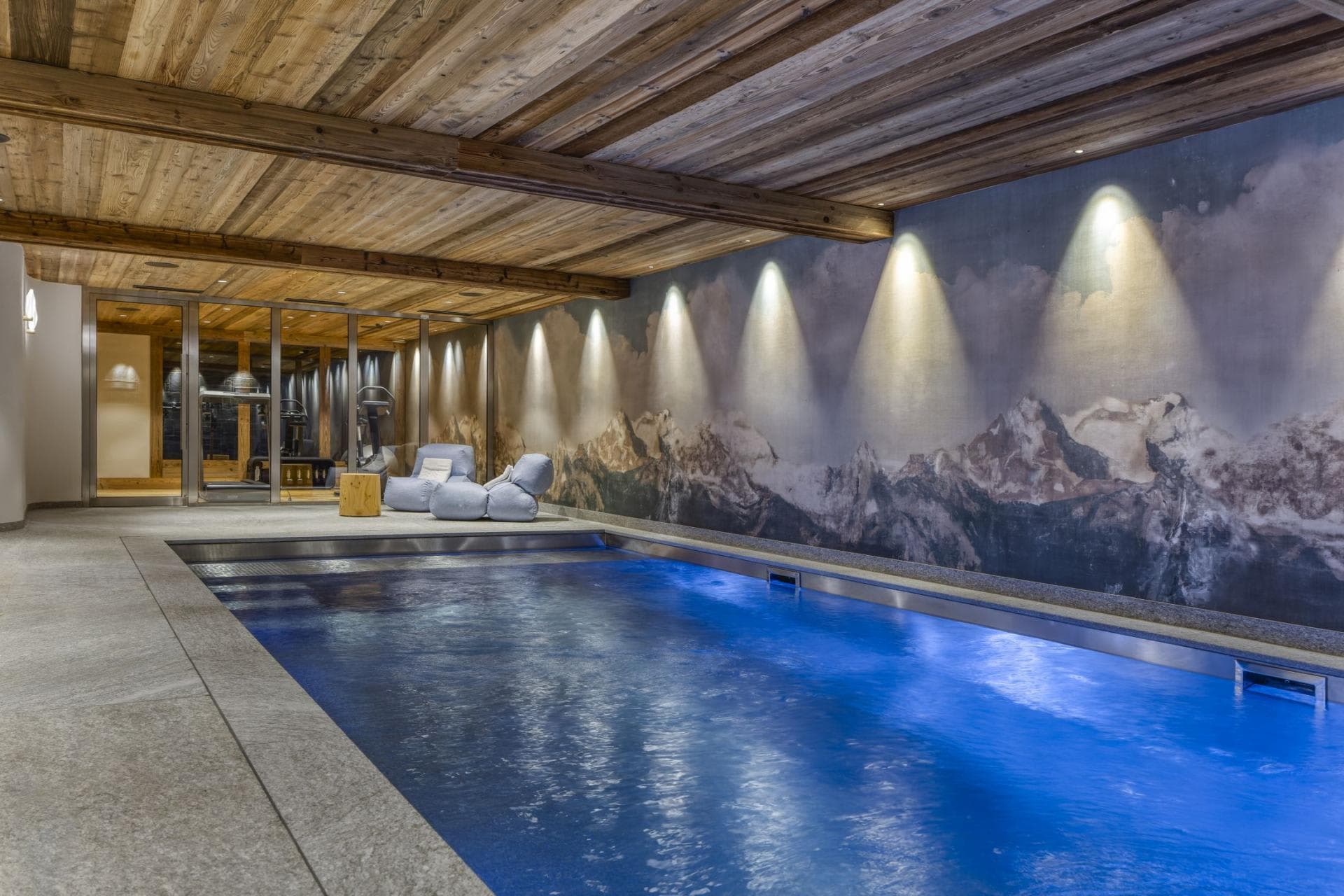 Indoor pool with integrated lighting and adjacent glass-walled gym