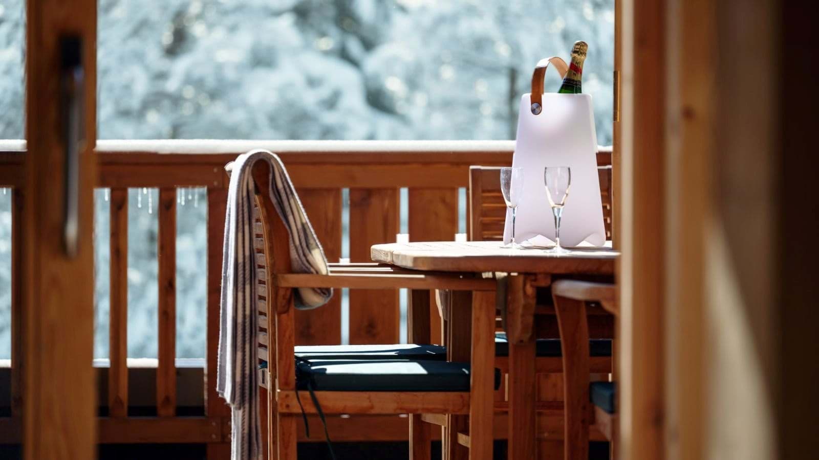Private balcony with wooden table and chairs; snowy forest backdrop