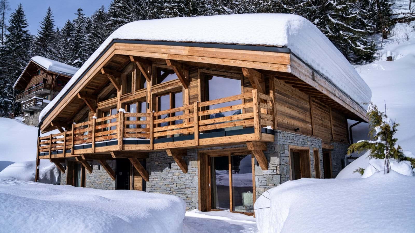 Ski-in chalet exterior with wraparound timber balcony and stone facade