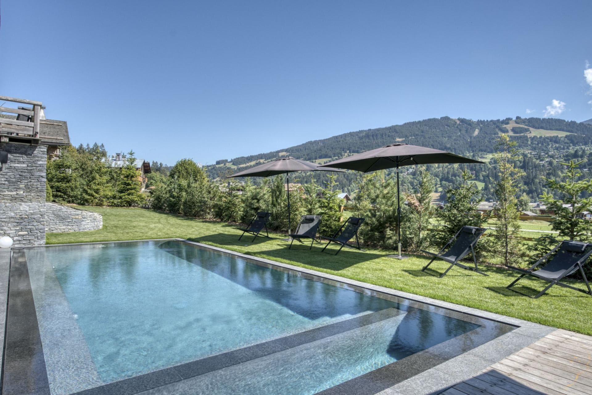 Heated infinity pool with mountain views and poolside lounger seating