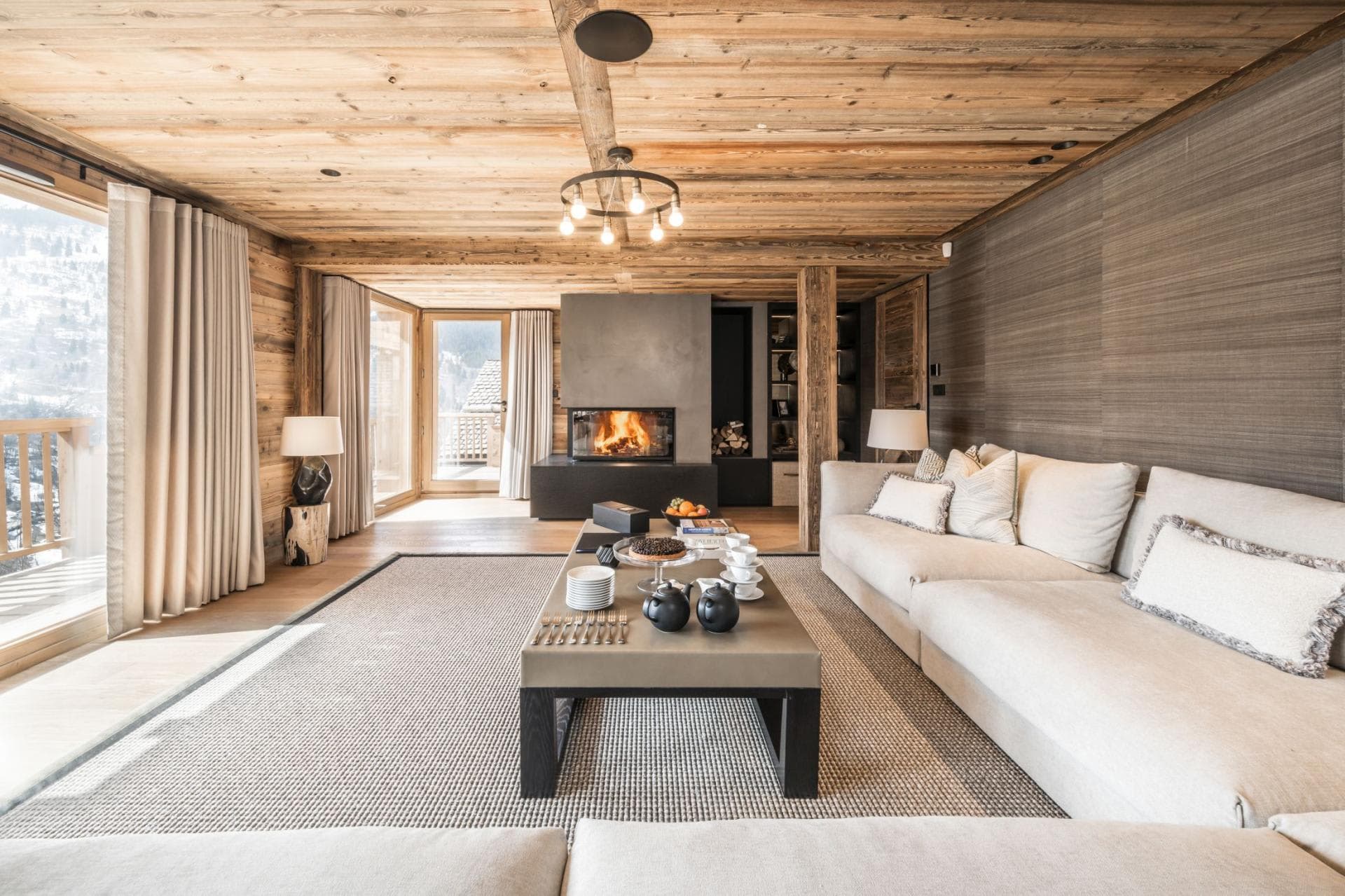 Living area with wood-burning fireplace and floor-to-ceiling mountain view windows