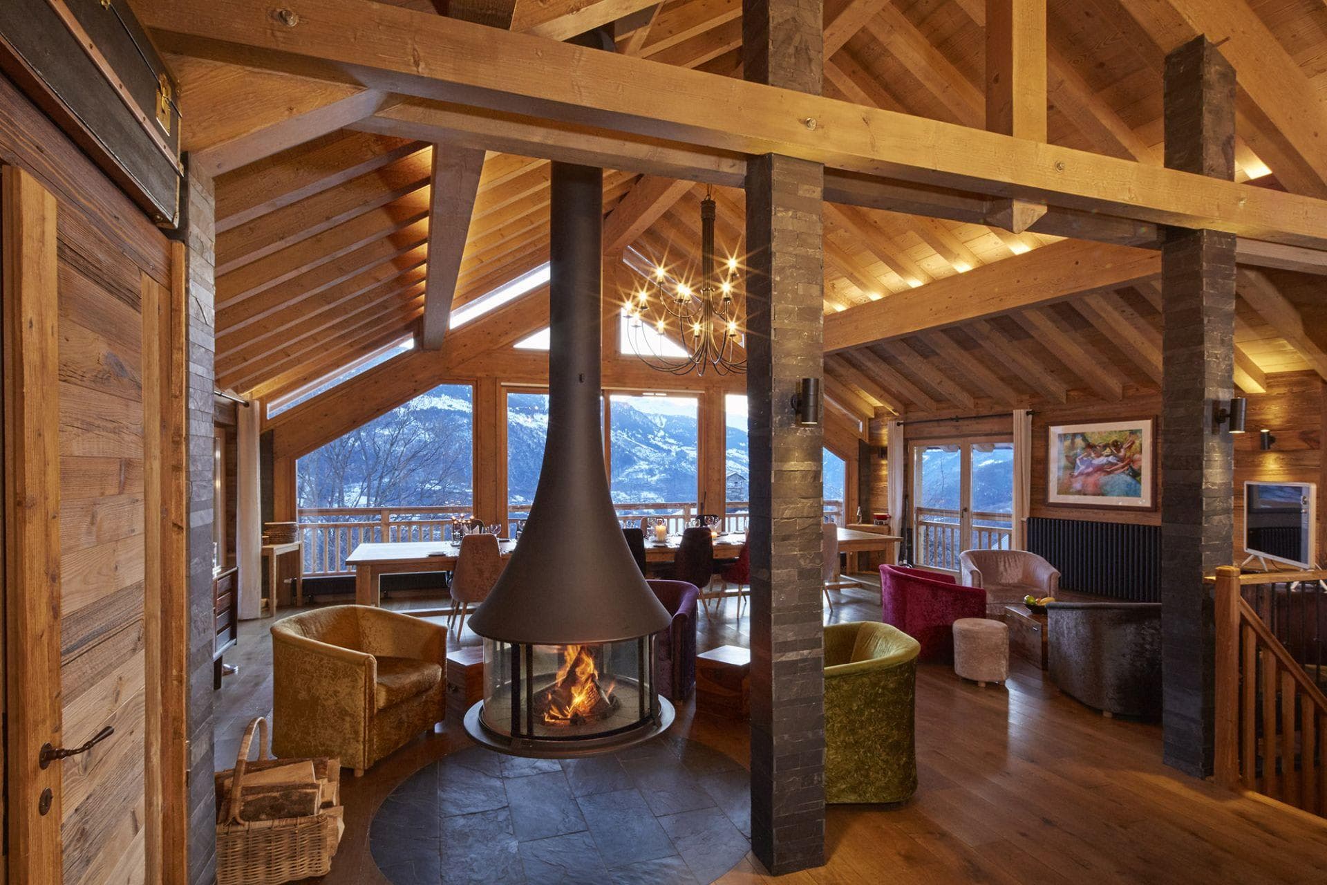 Open-plan living area with suspended fireplace and mountain-view dining