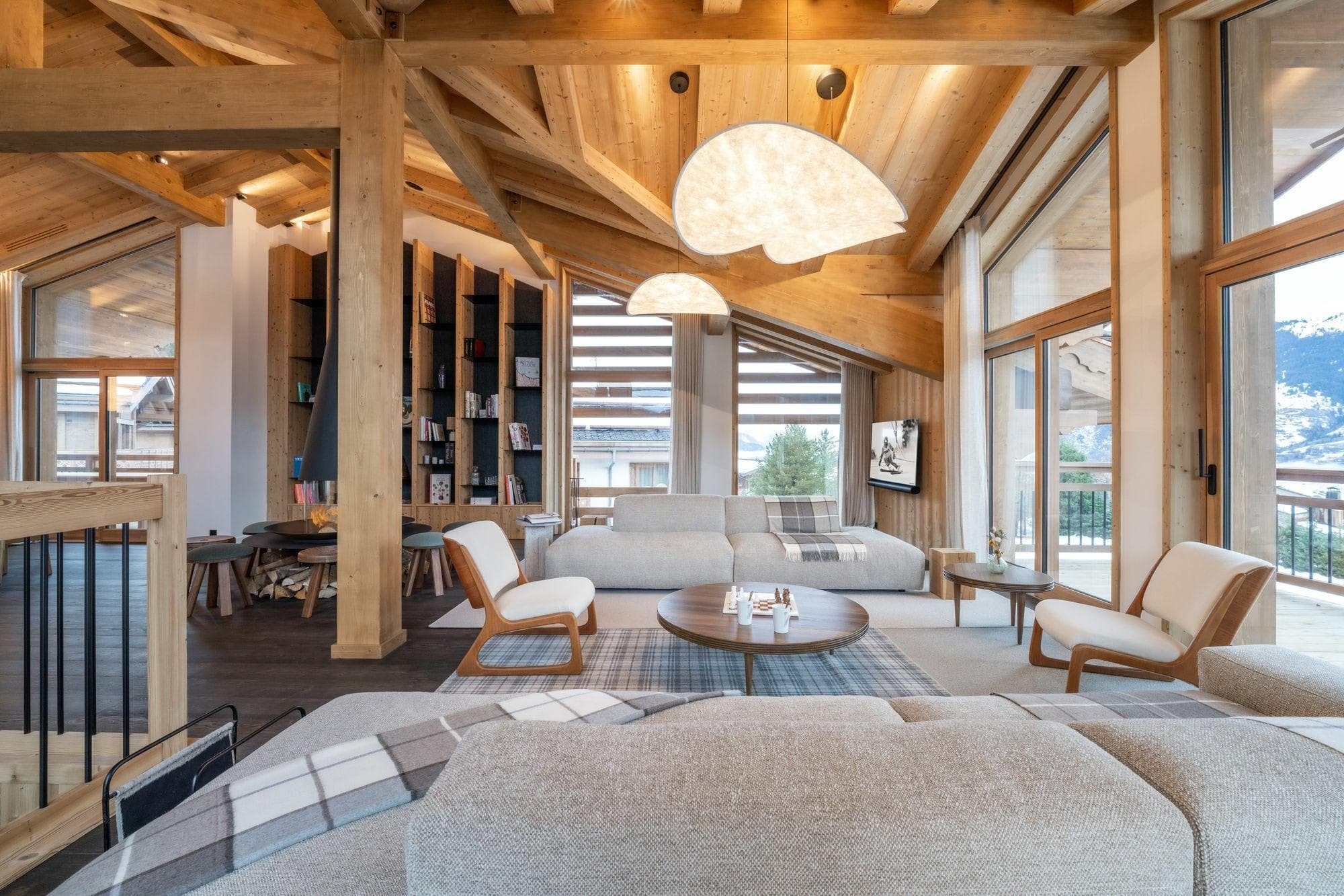 Open-plan living room with exposed beam ceiling, floor-to-ceiling windows, and valley views