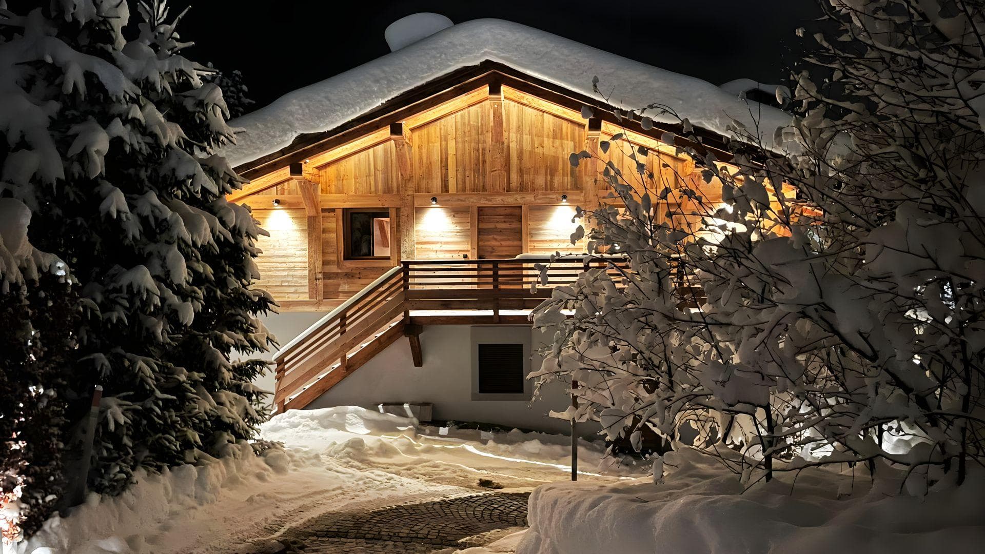 Timber chalet exterior featuring private balcony and snow-cleared stone driveway