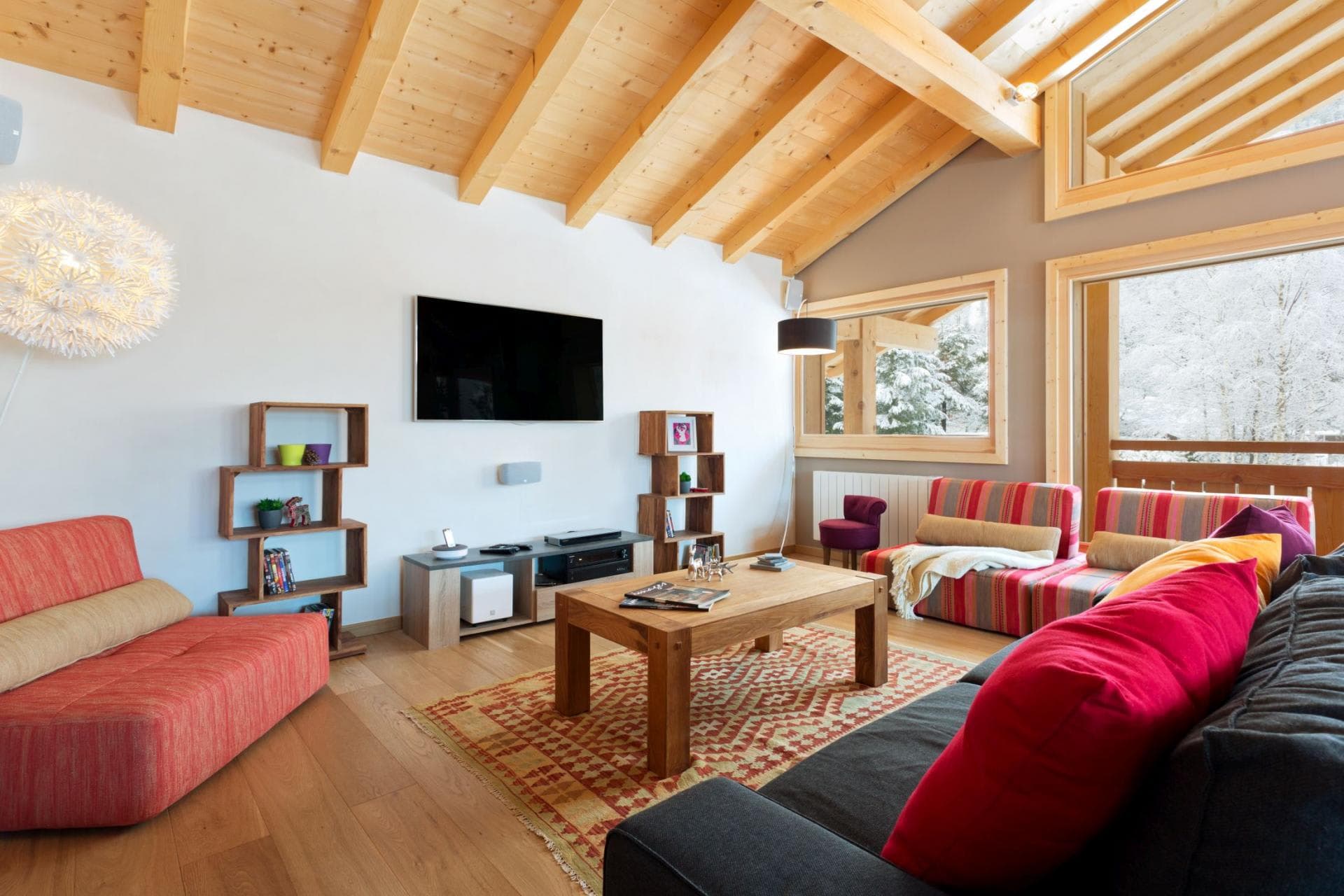 Living area with vaulted timber ceilings and snowy forest views