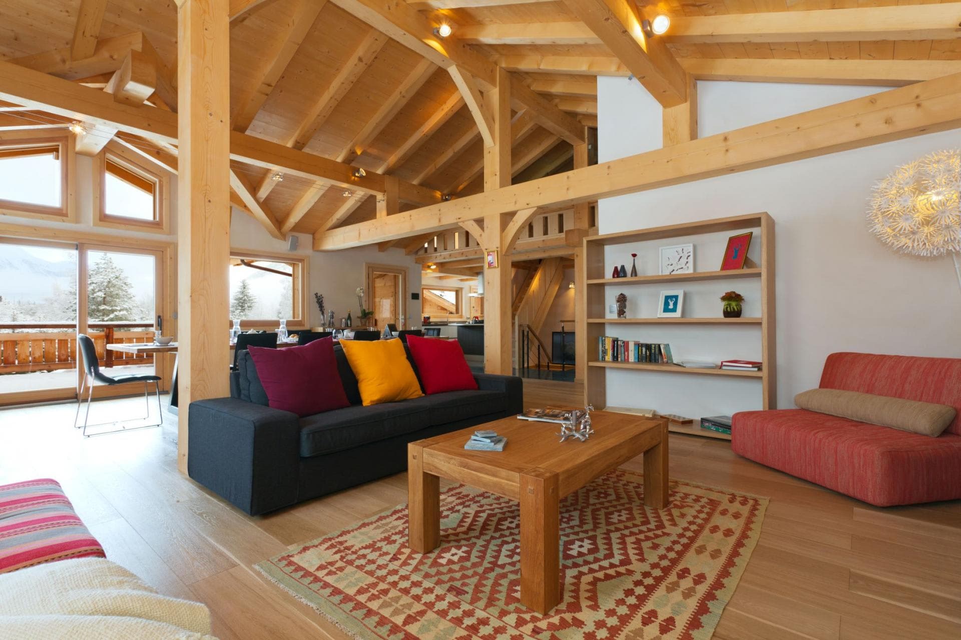 Open living area with vaulted timber ceilings and access to snow-view balcony