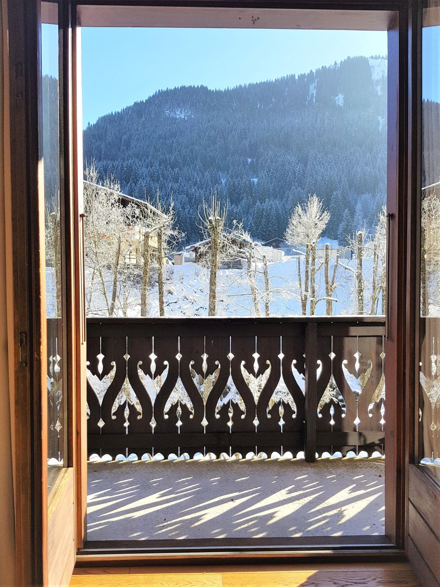 Private balcony with decorative wood railing and snowy mountain views