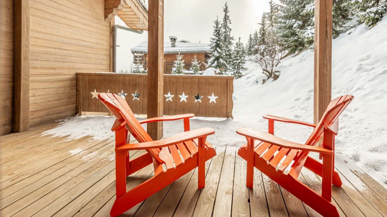 Covered wooden deck with Adirondack seating and snowy hillside views
