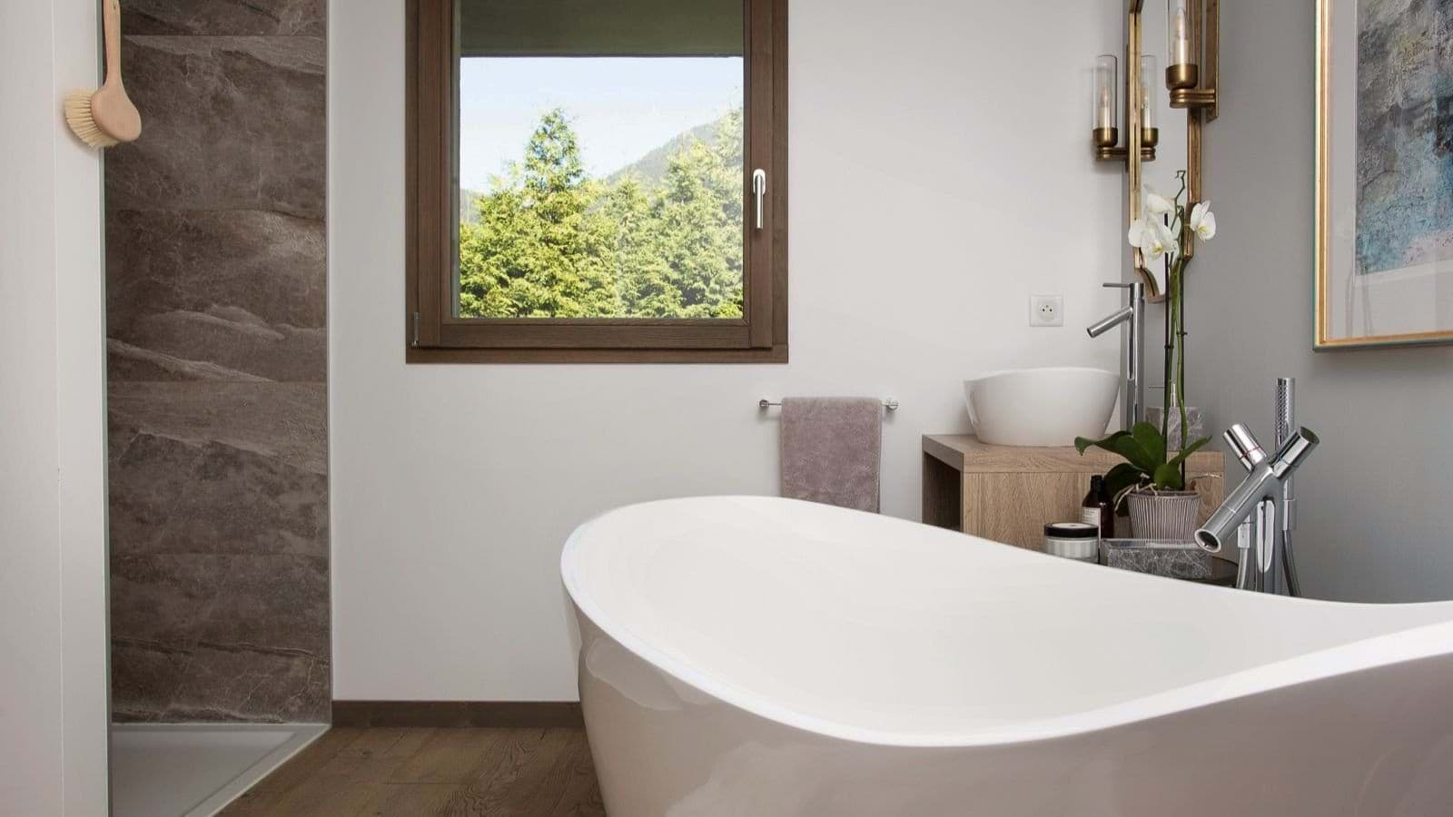 Bathroom with soaking tub, walk-in shower, and forest views