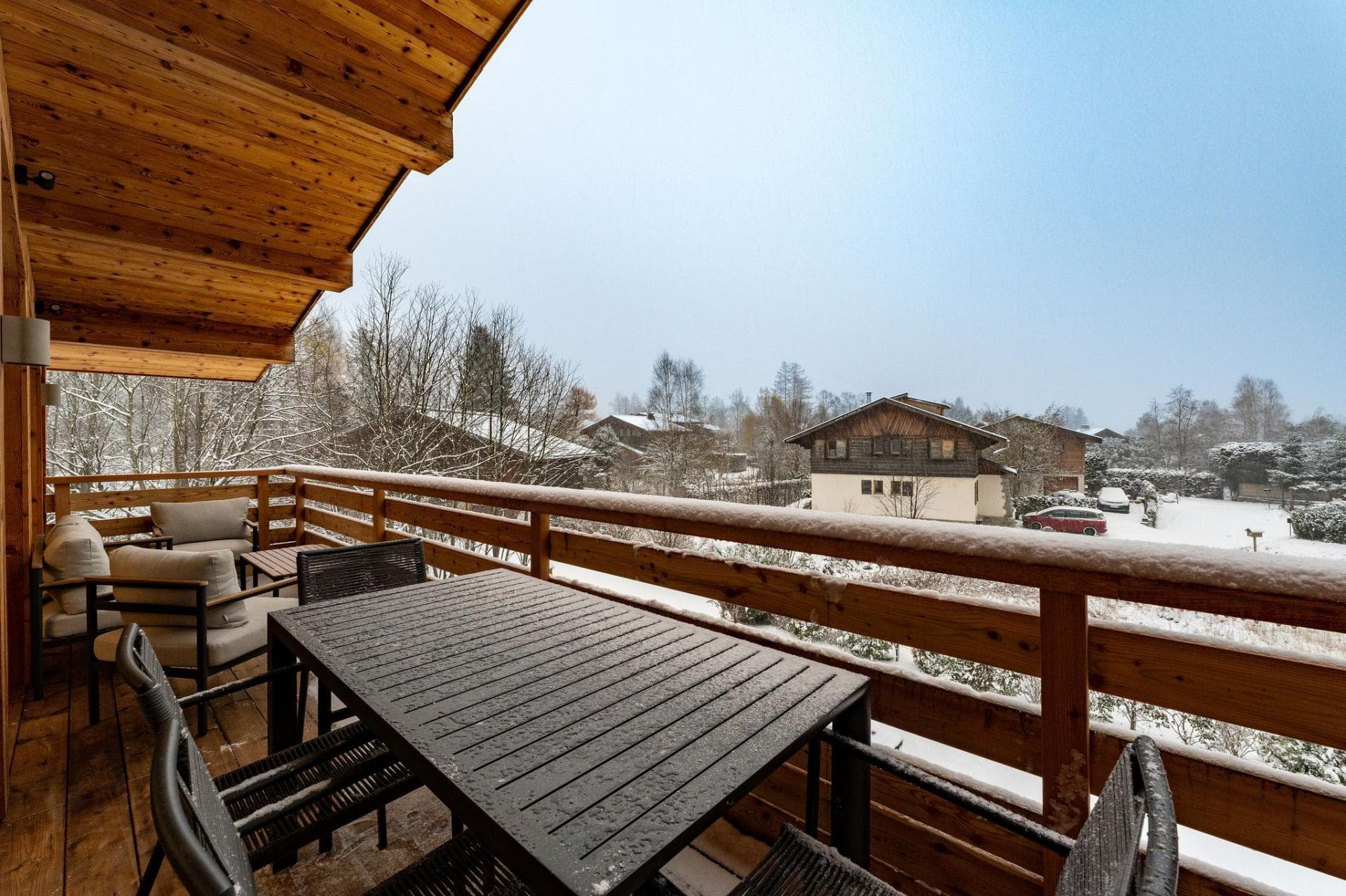 Covered wooden balcony with dining table and mountain village views