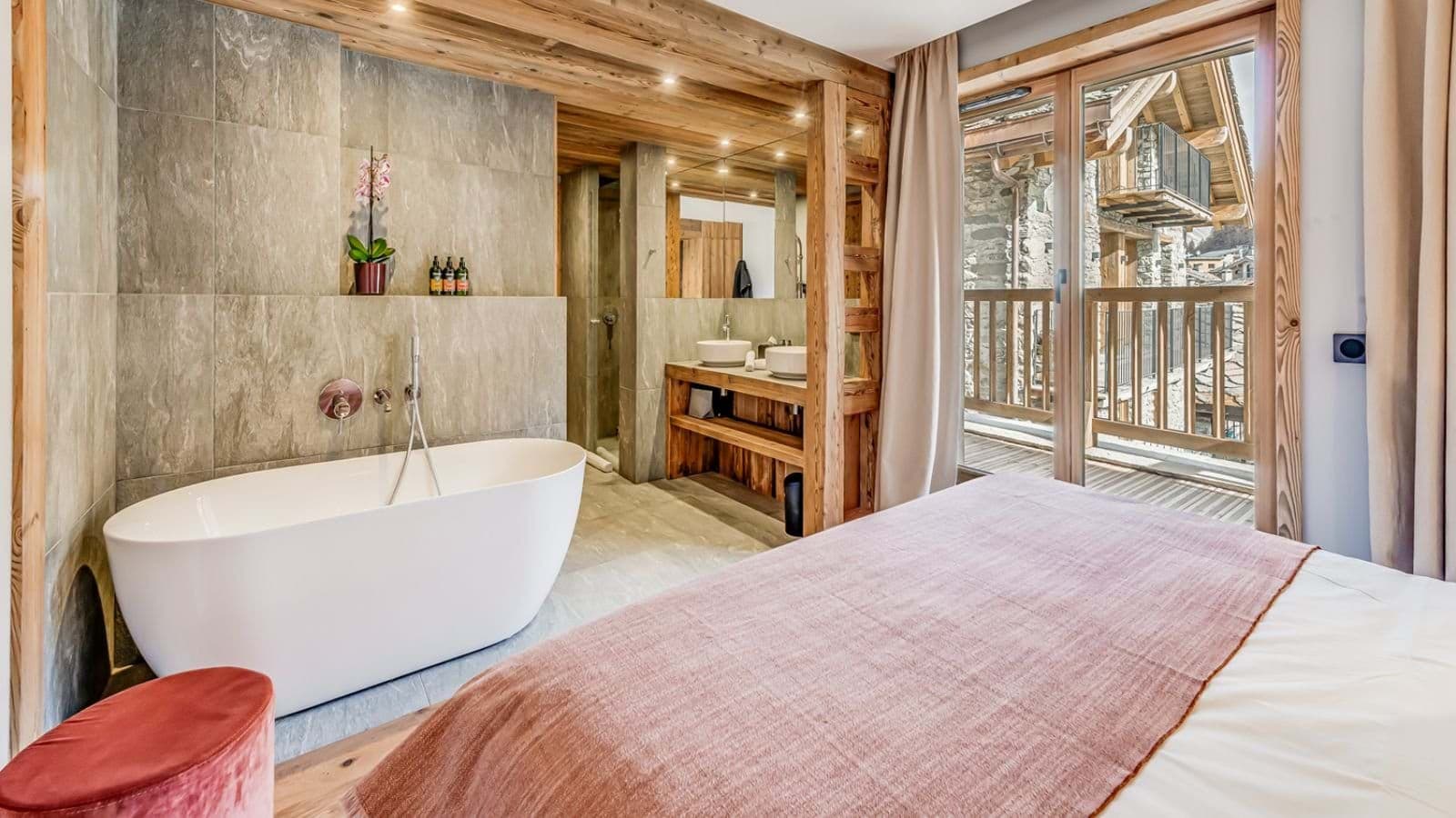 Open-plan bedroom and ensuite with freestanding tub and balcony access