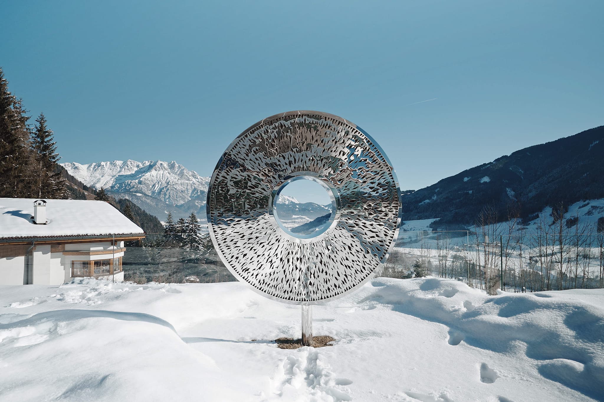 outdoor mirrored sculpture framing mountain views on property grounds