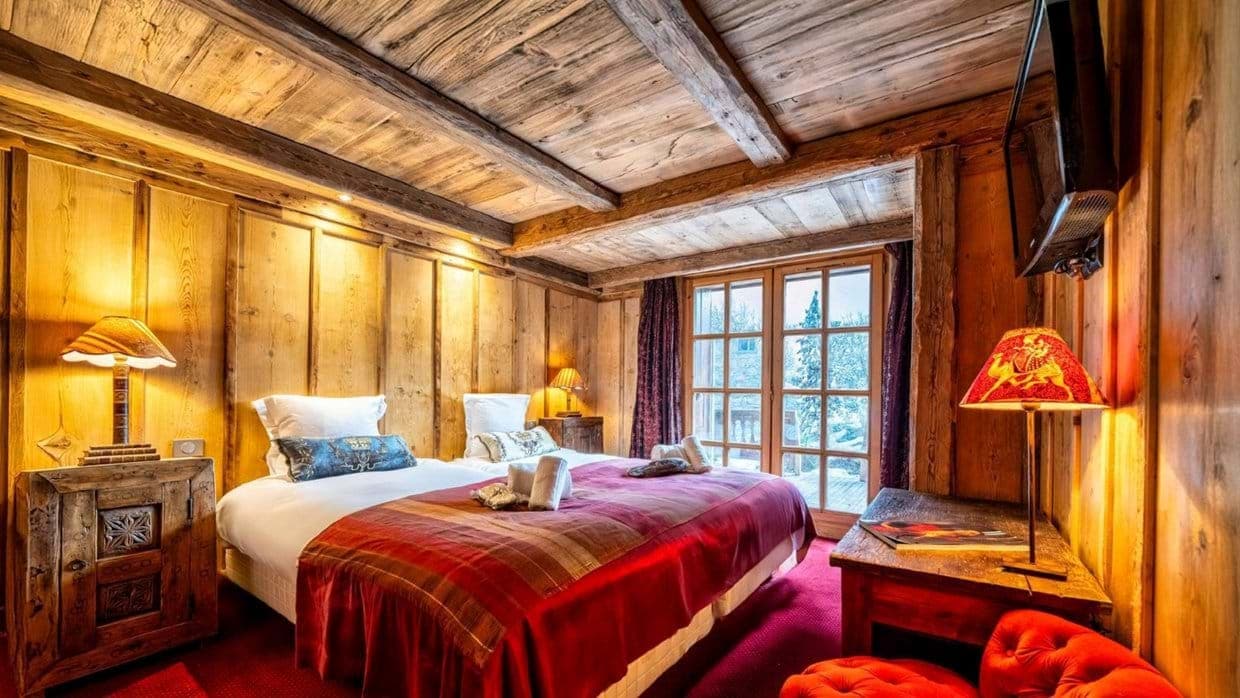 Twin bedroom with rustic wood paneling and balcony access