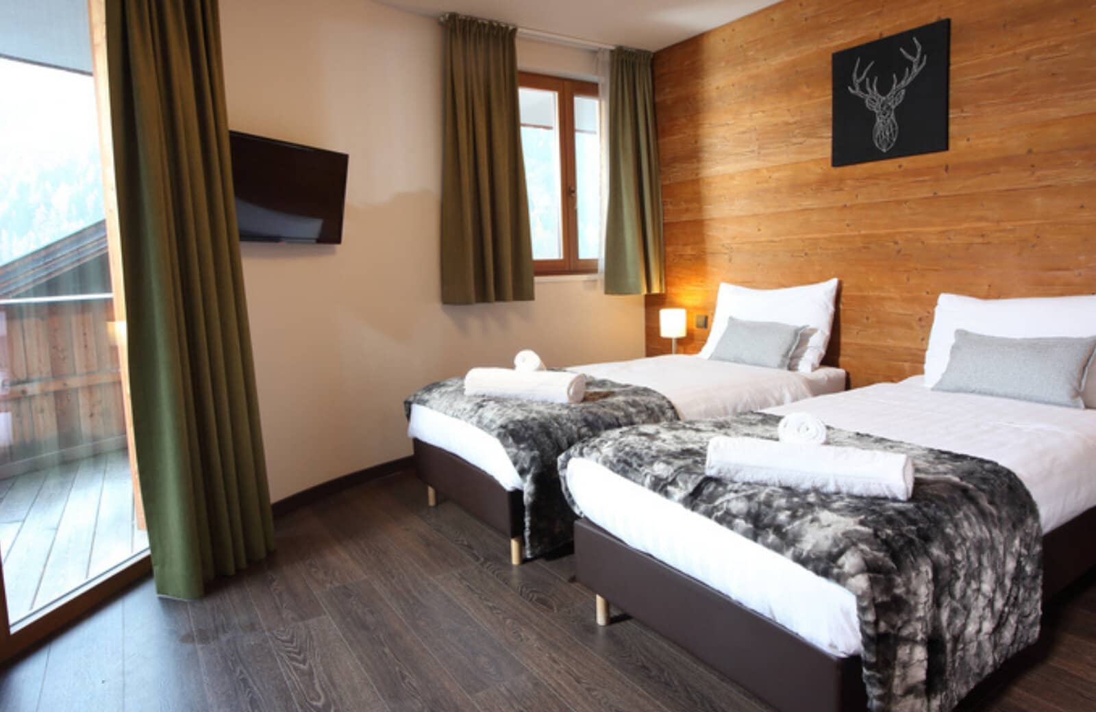 Guest bedroom with twin beds, wall-mounted TV, and balcony access