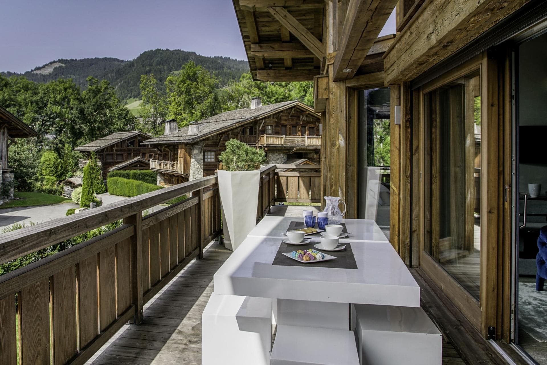Covered balcony with dining table and mountain village views