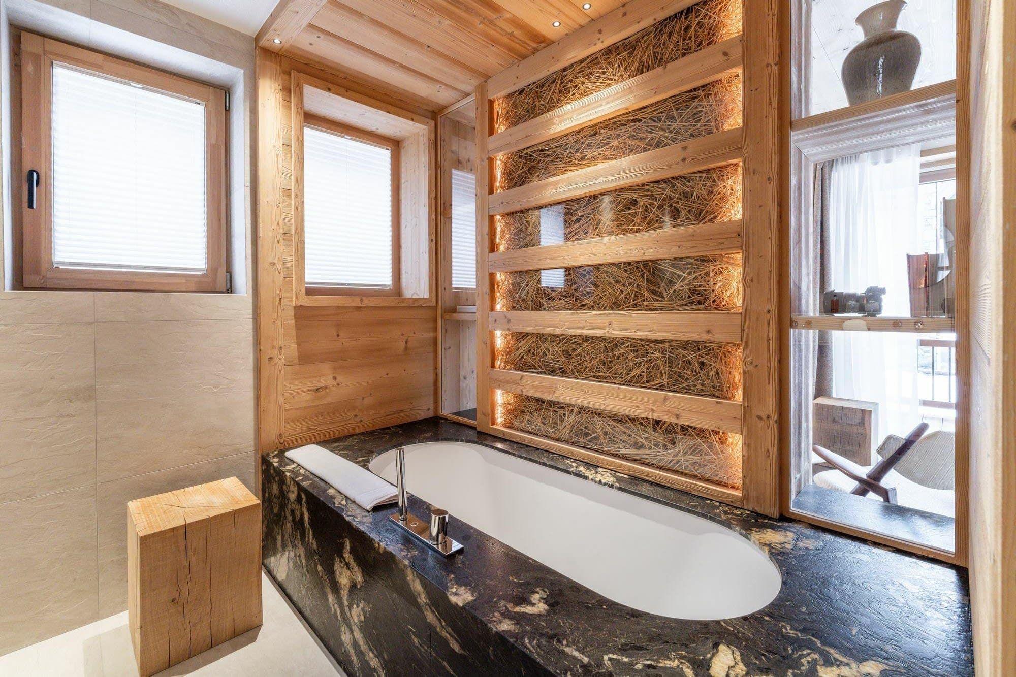 Soaking tub with black marble surround and illuminated hay-wall feature