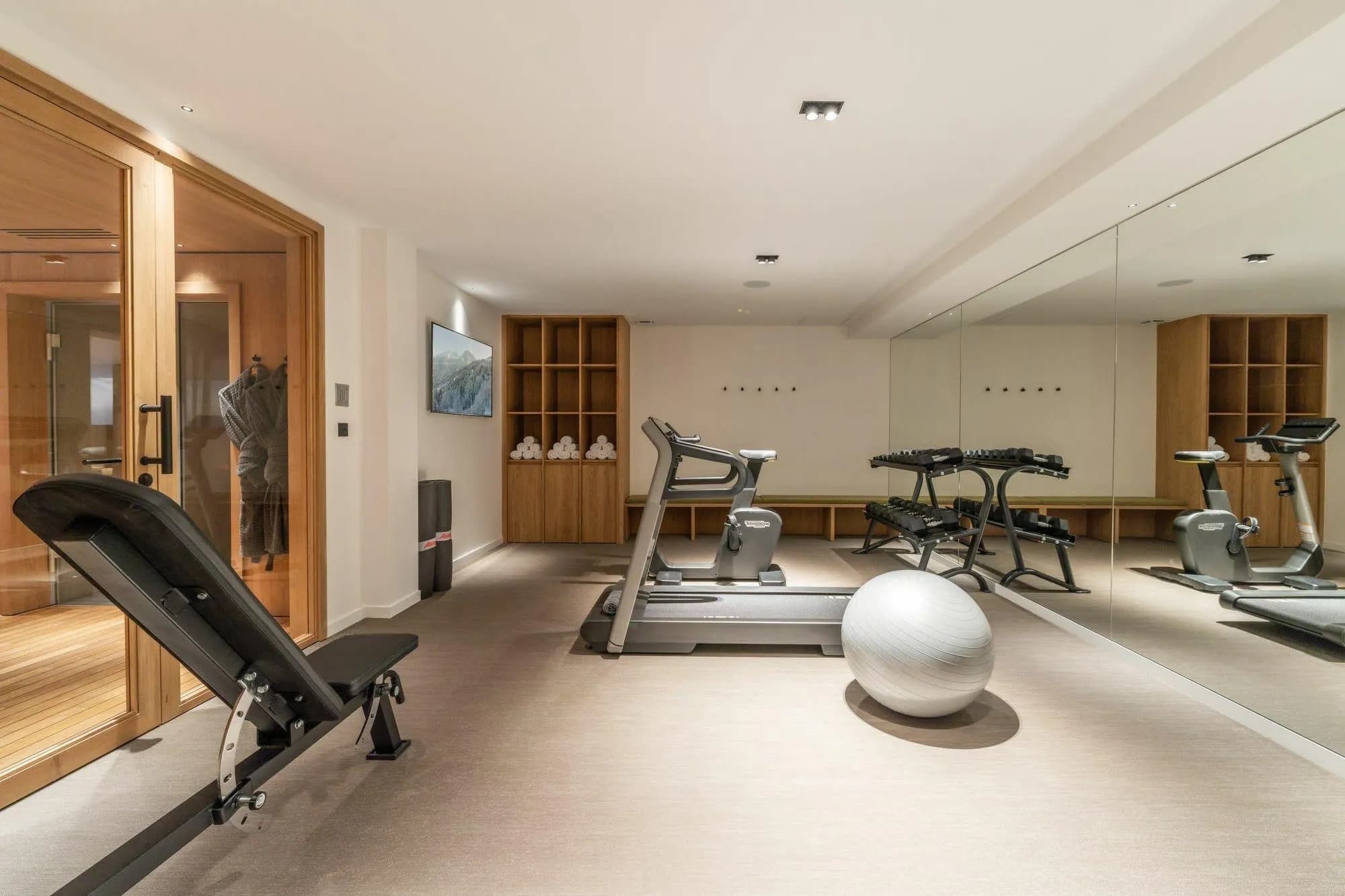 Fitness room with exercise equipment, free weights and an adjacent sauna