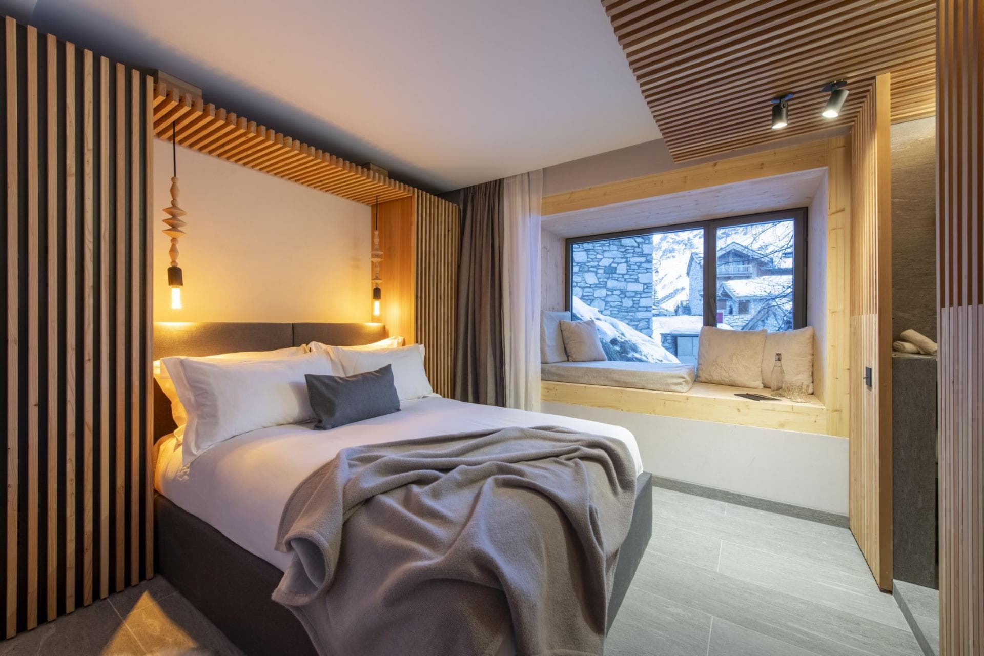 Bedroom with queen bed and cushioned window seat overlooking snowy village