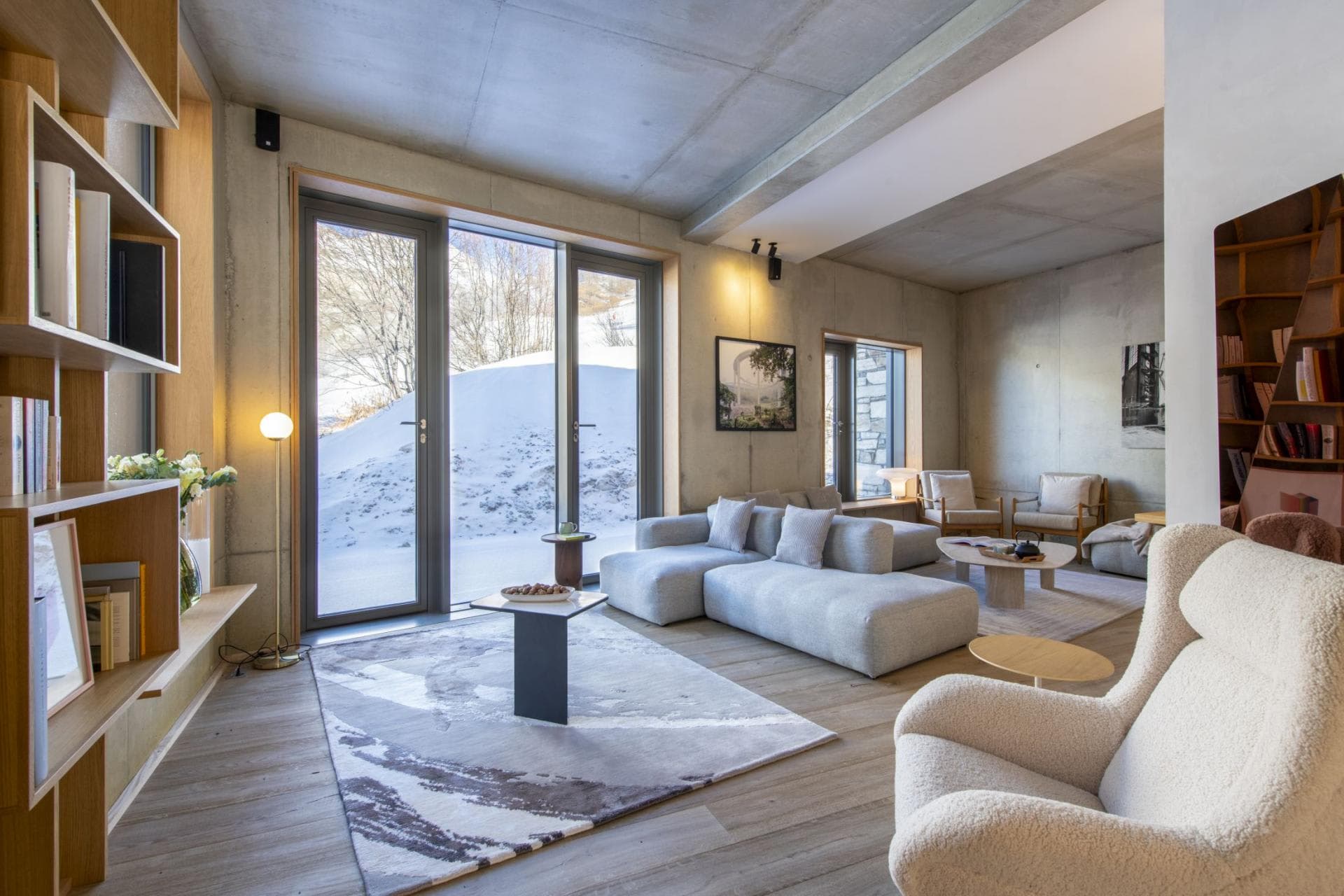 Living area with modular seating and floor-to-ceiling windows overlooking snow-covered hills