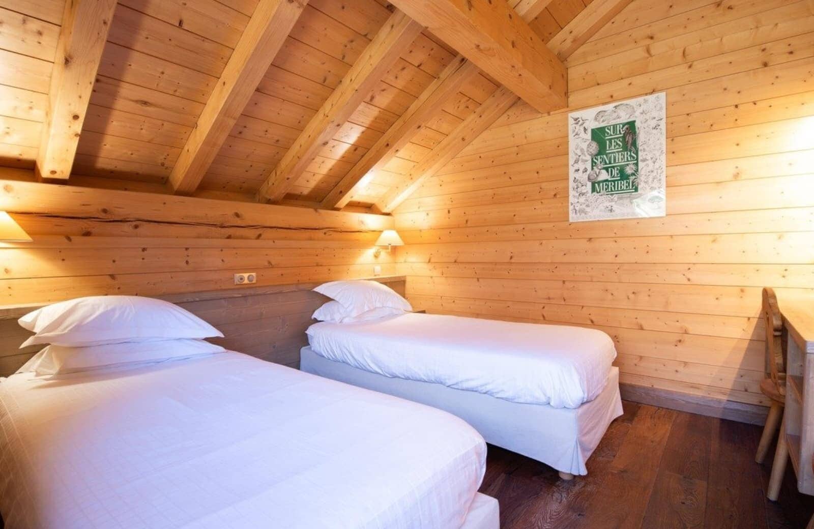 Attic bedroom with twin beds, vaulted timber ceilings, and work desk