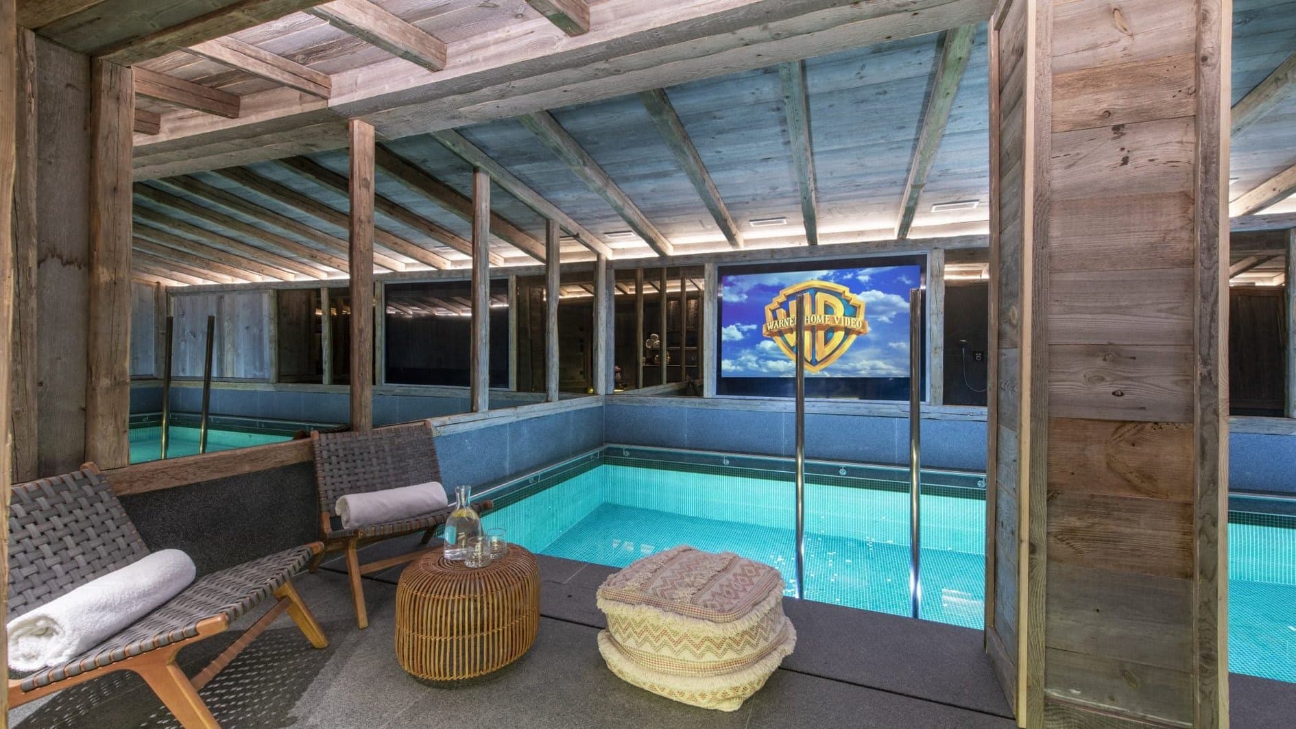 Indoor pool area with poolside cinema screen and lounge seating