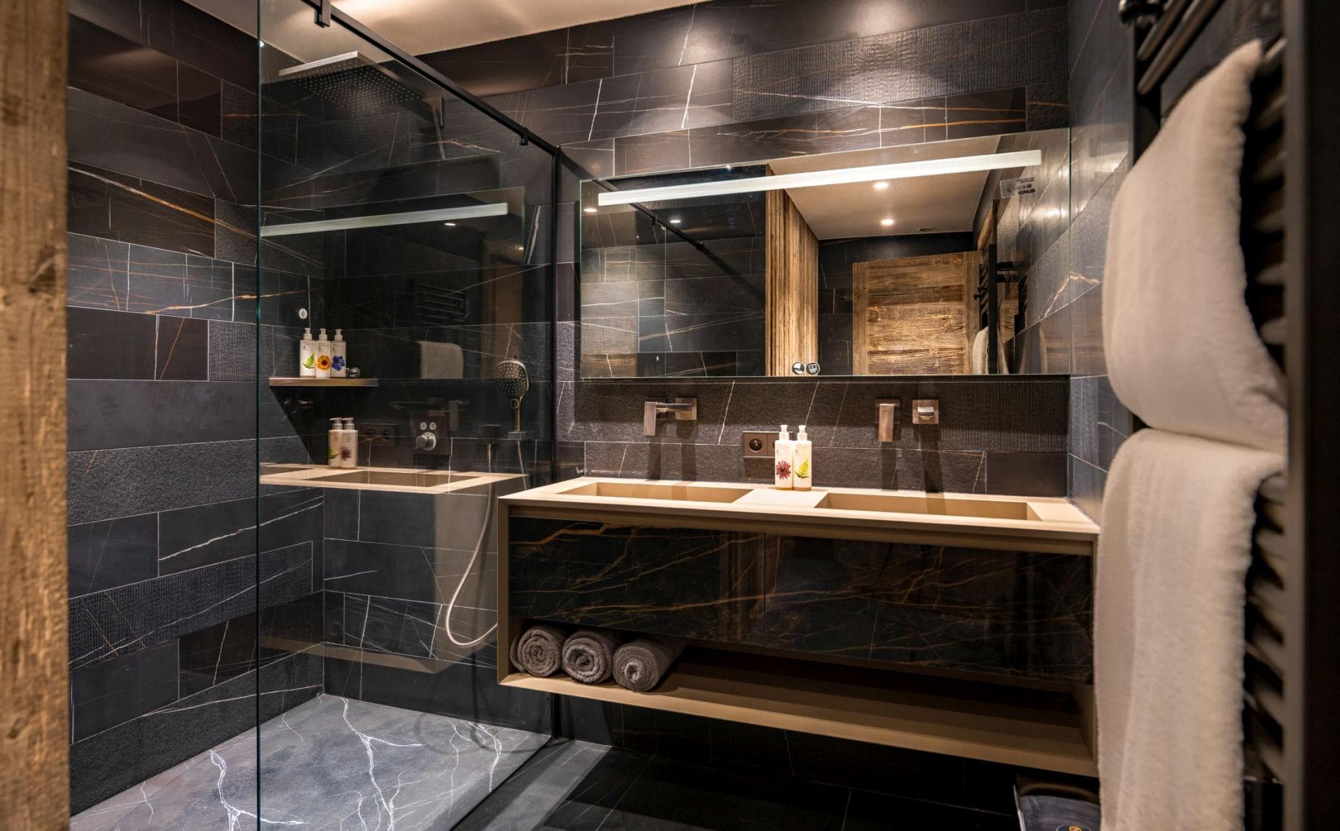 Bathroom with dual vanity, heated towel rack, and walk-in rain shower