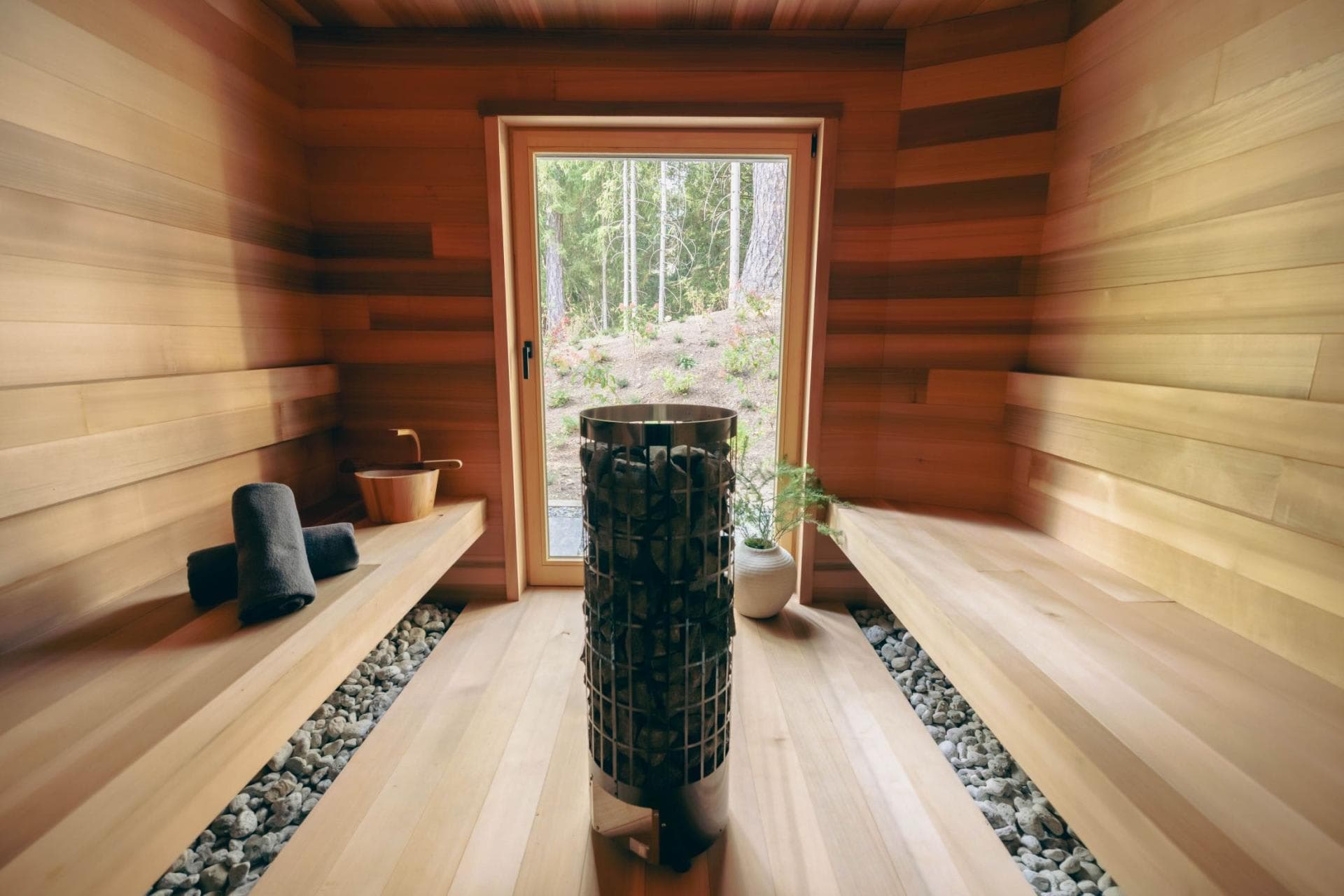 Cedar sauna with electric heater and floor-to-ceiling forest view