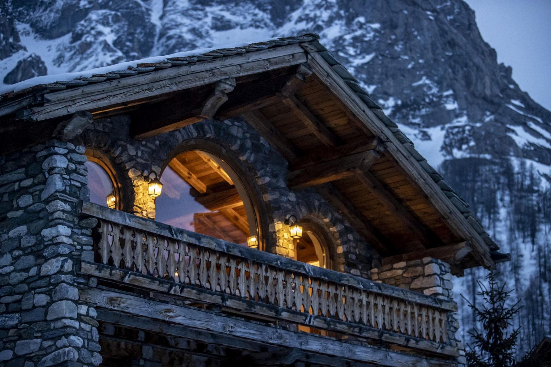 Stone chalet exterior with hand-carved balcony and mountain views