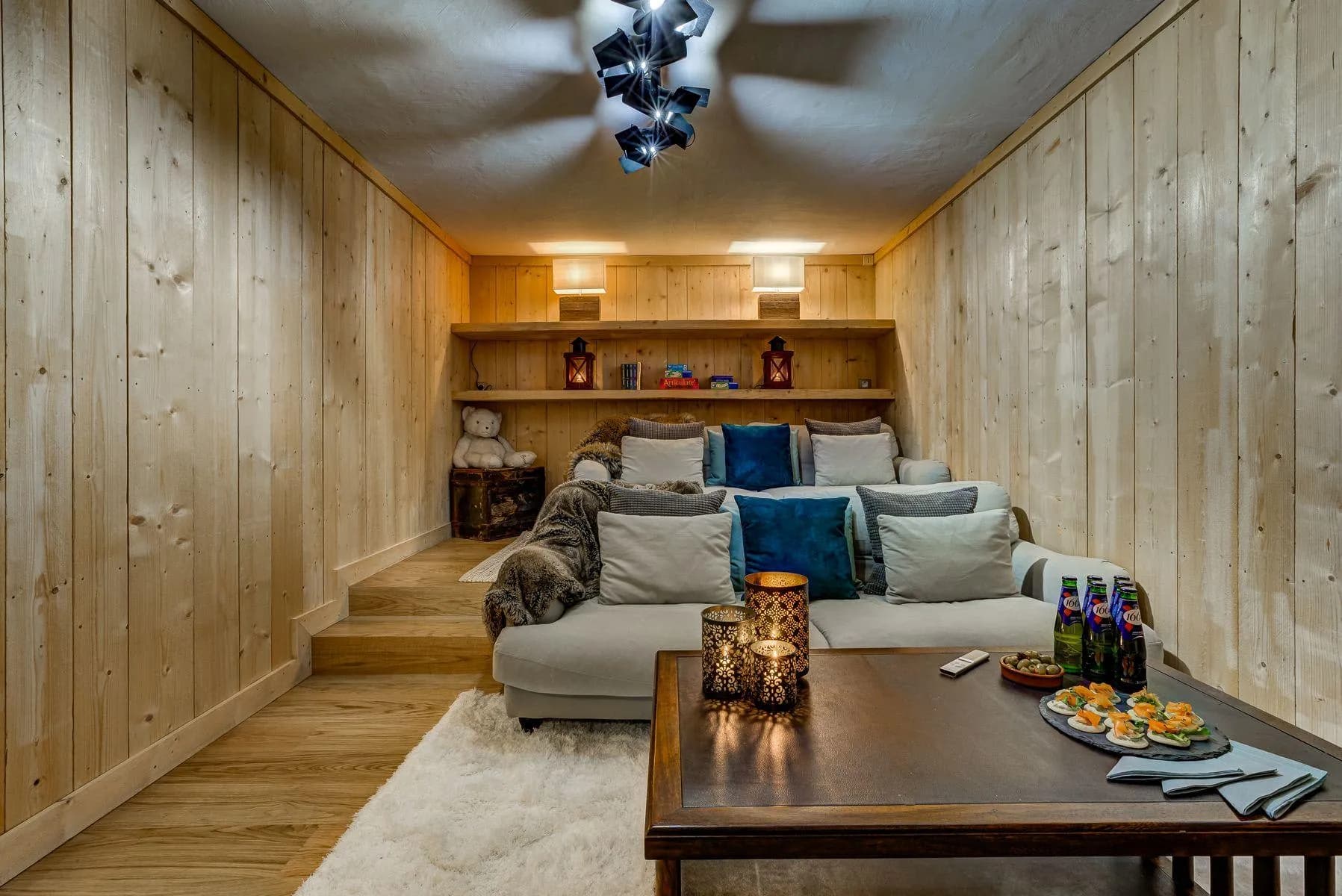 Cinema room with sectional seating, a wall-mounted screen and built-in shelving