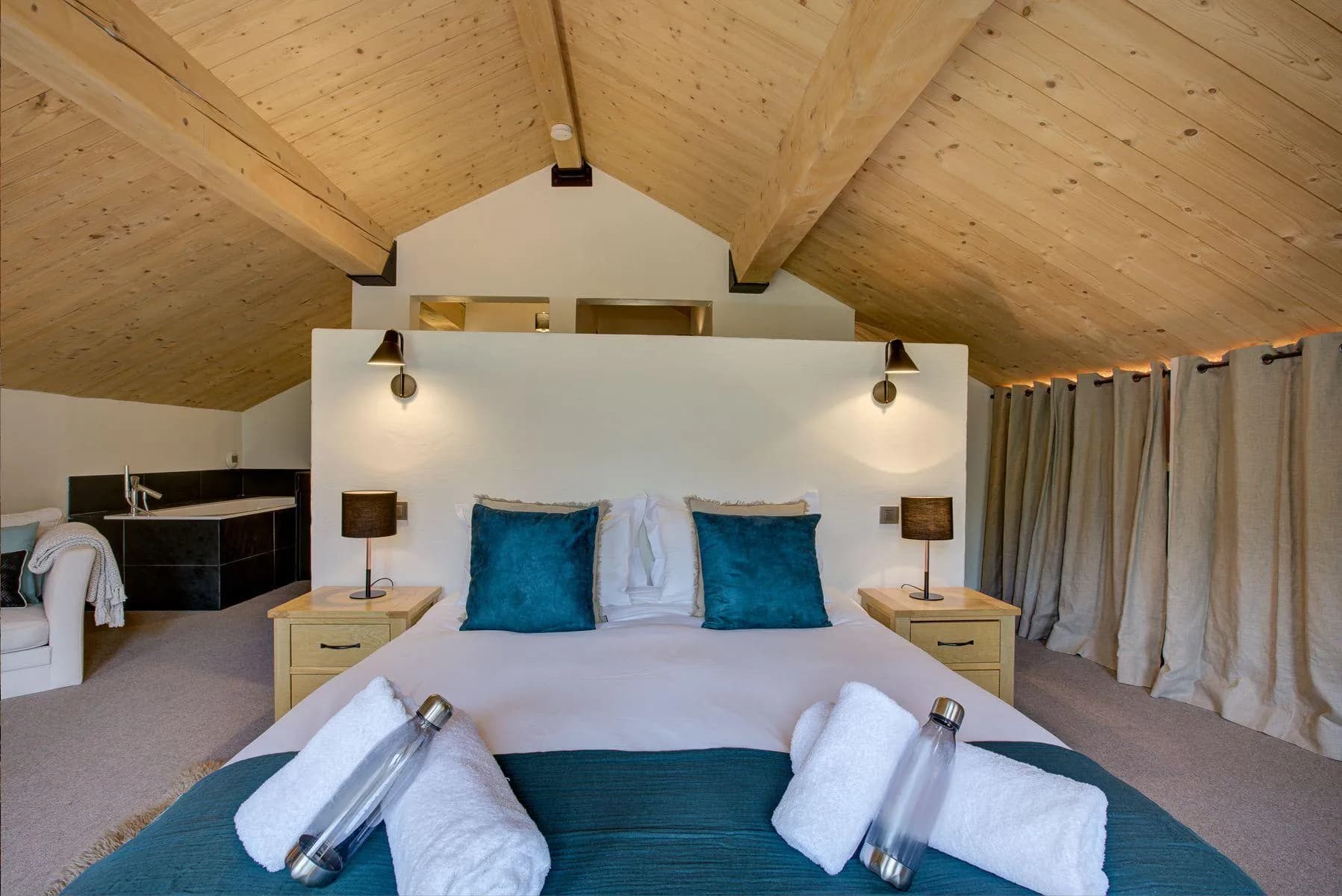 Master bedroom beneath a vaulted timber ceiling with its en-suite bathroom beyond
