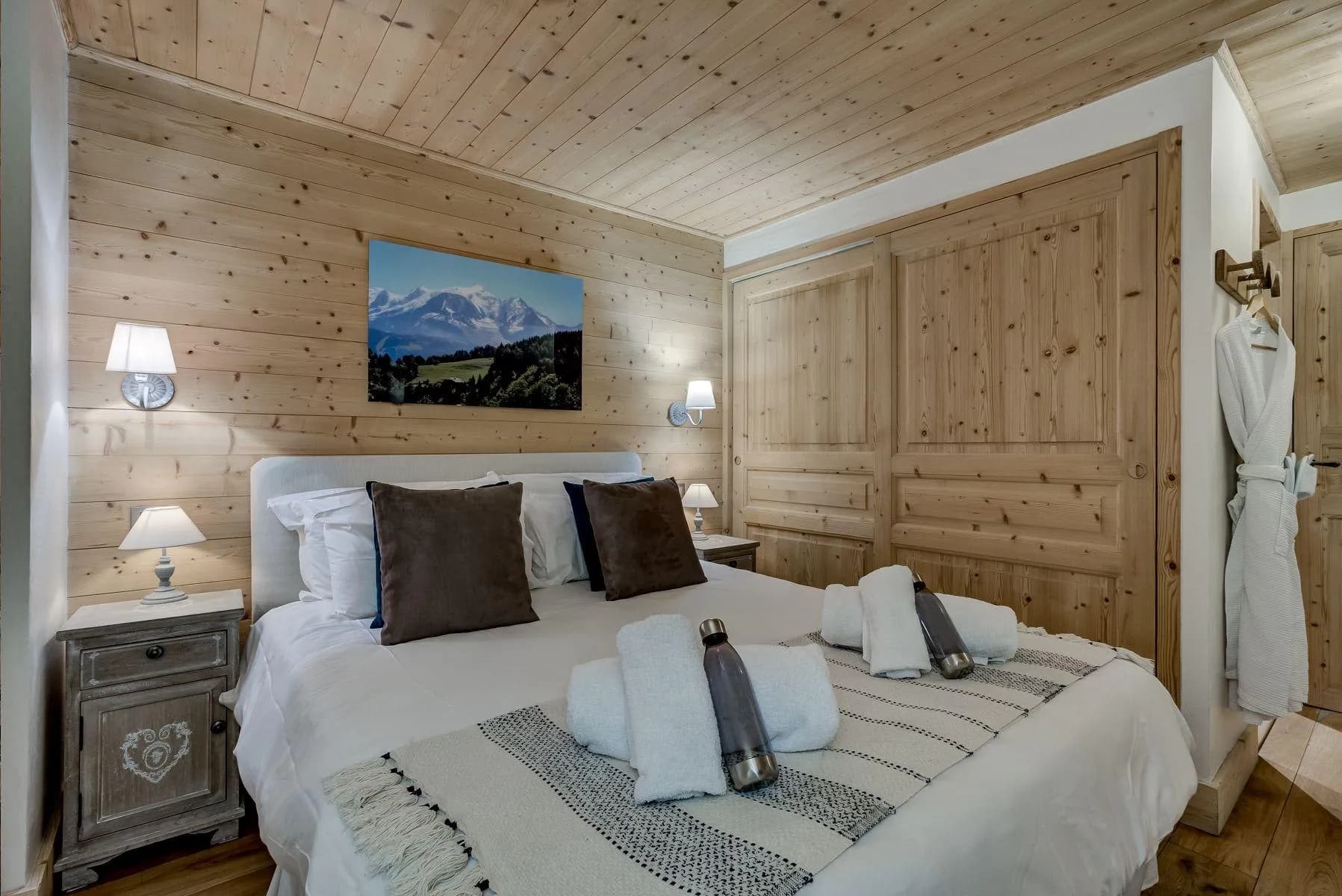 Double bedroom with timber walls, mountain artwork and wardrobe space