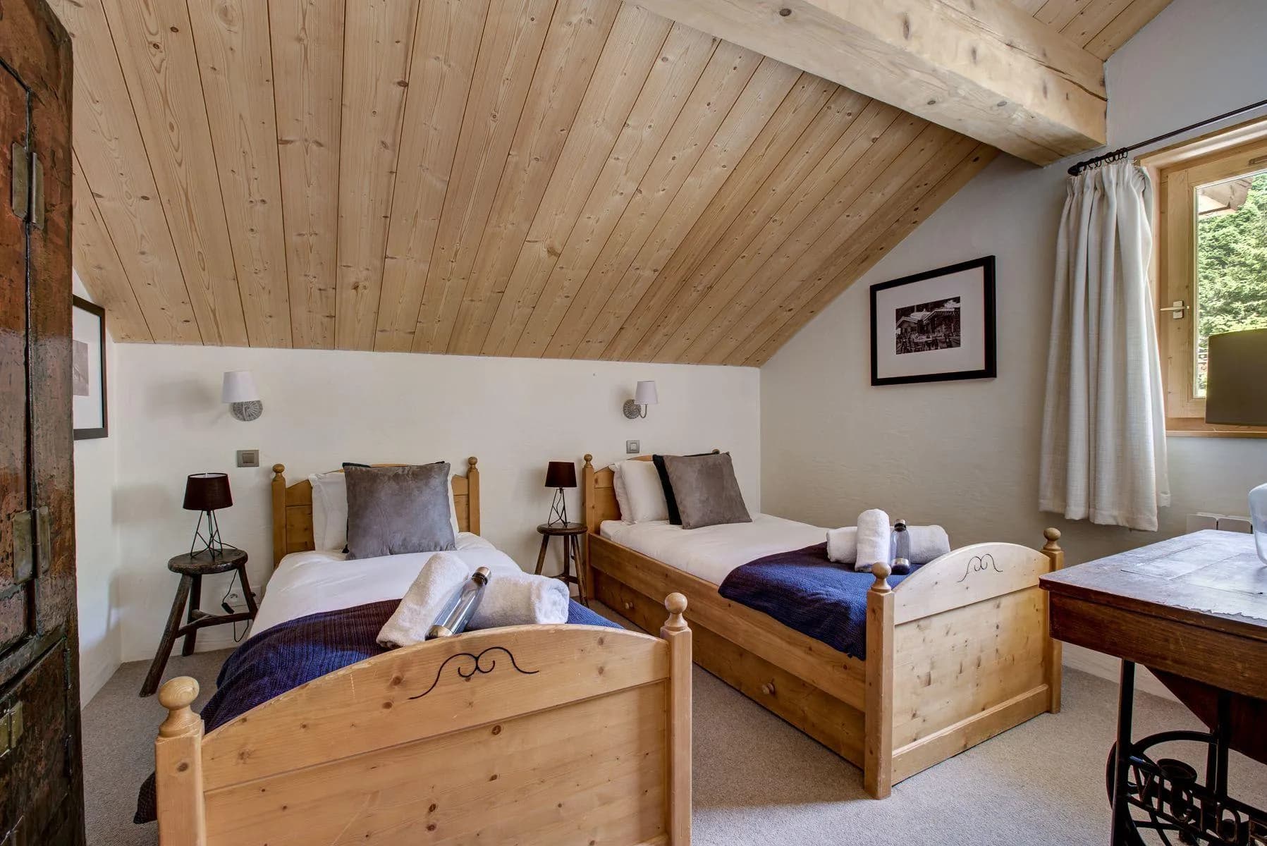 Twin bedroom beneath a sloping timber ceiling