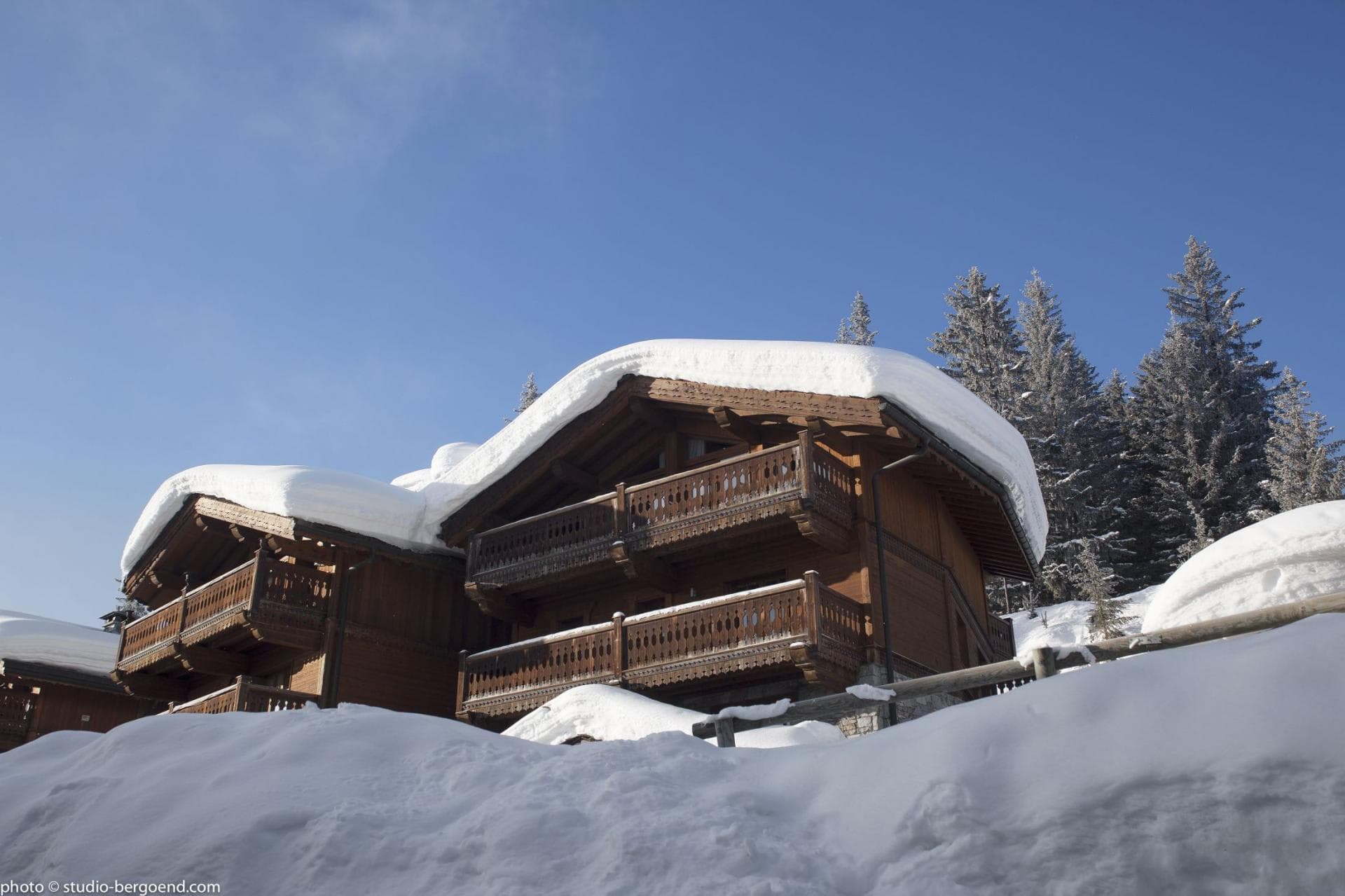Timber chalet exterior with multiple private balconies in a snowy alpine setting