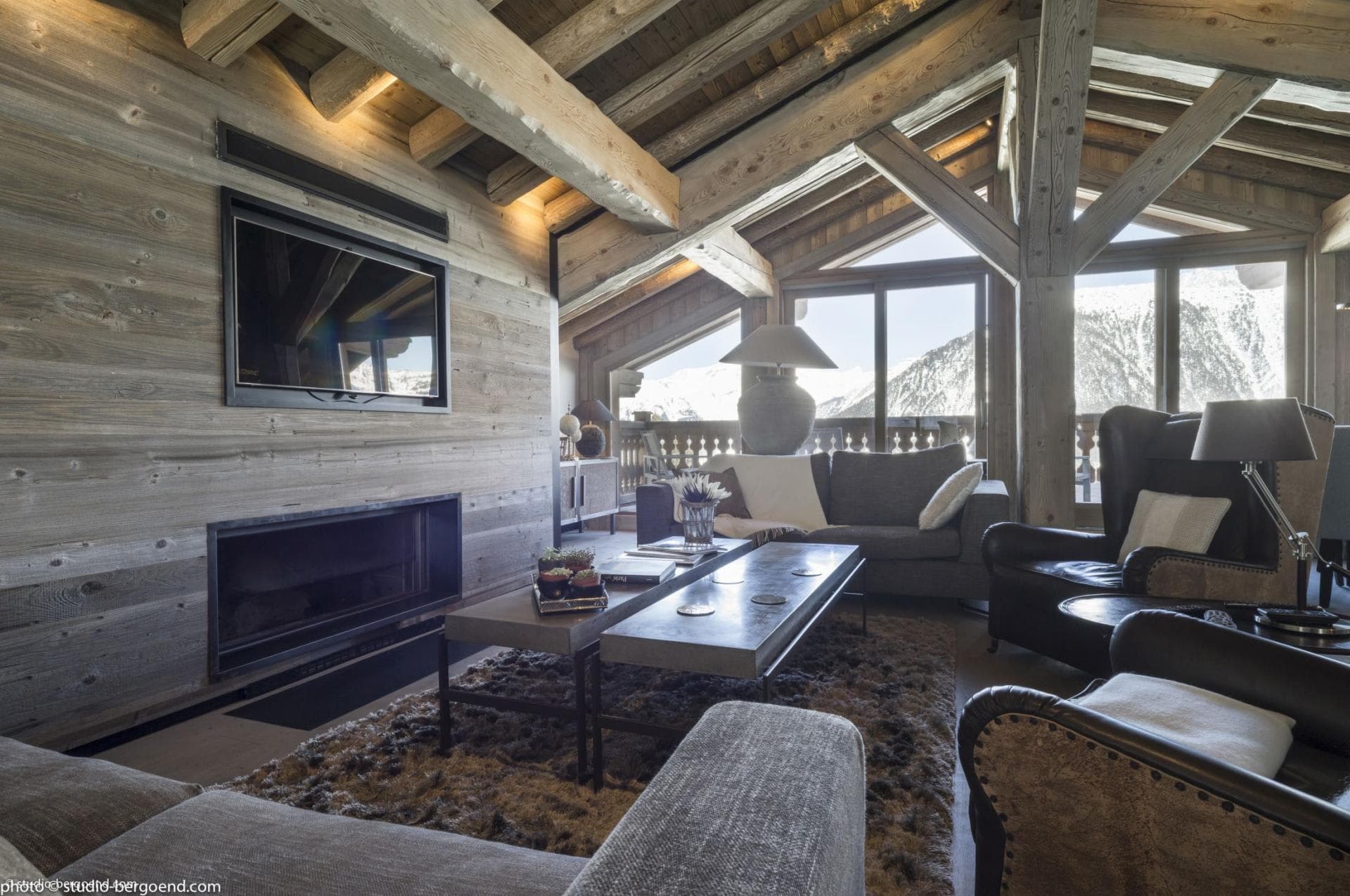 Living room with built-in fireplace and mountain views from floor-to-ceiling windows