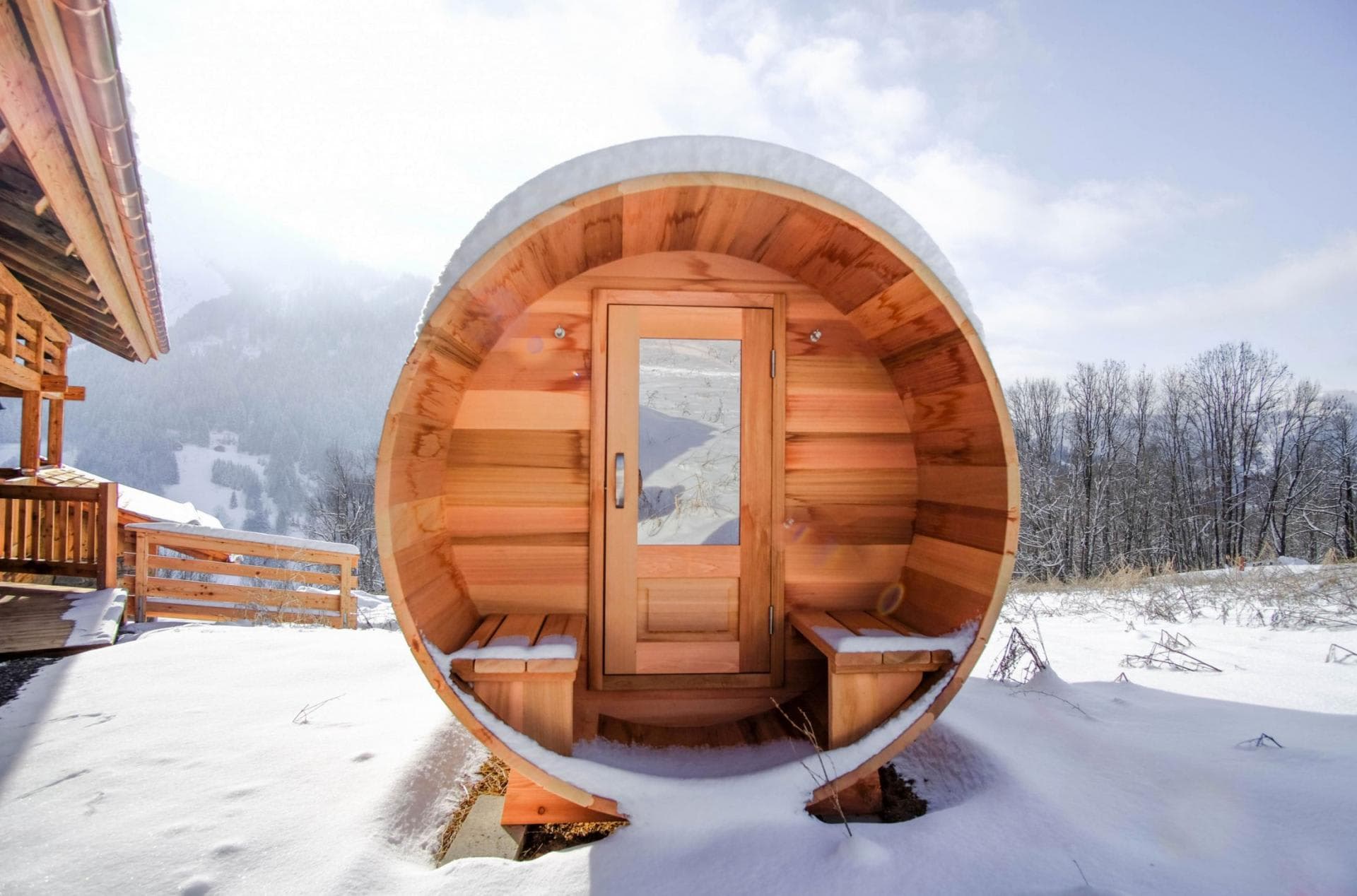 Outdoor barrel sauna with integrated porch seating and mountain views