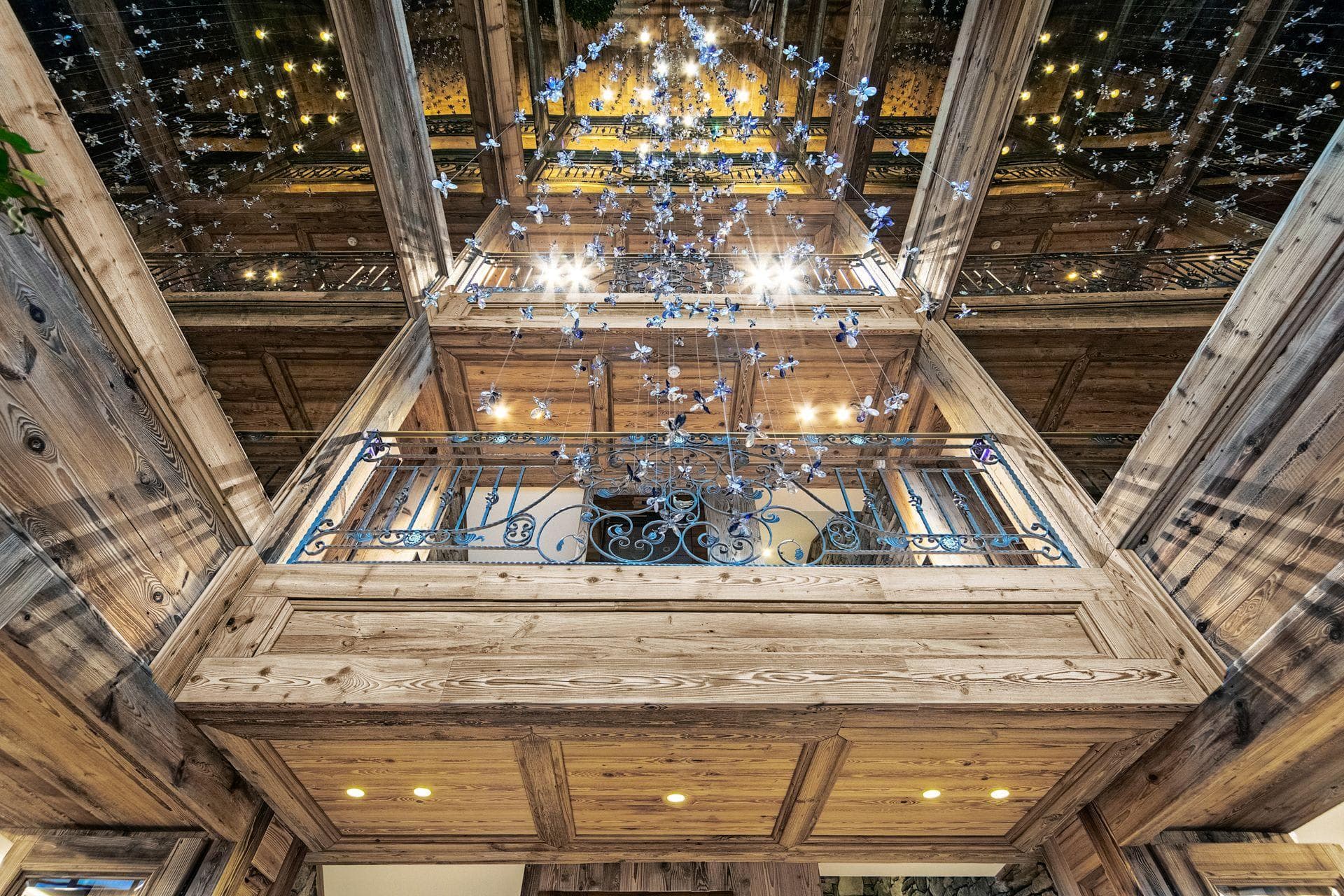 Multi-story timber atrium with glass ceiling and hanging butterfly installation