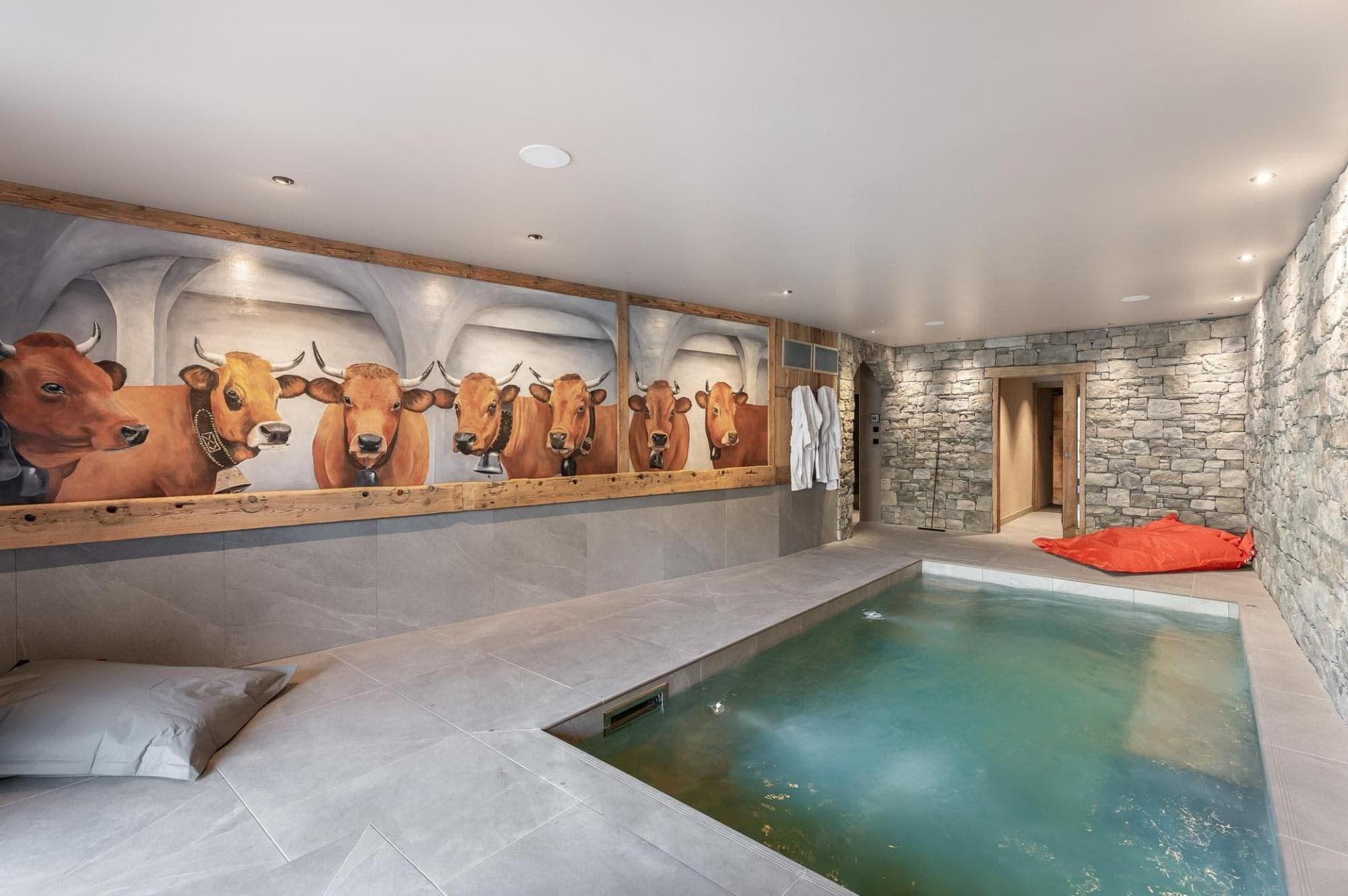 Indoor pool area with cow mural and stone walls