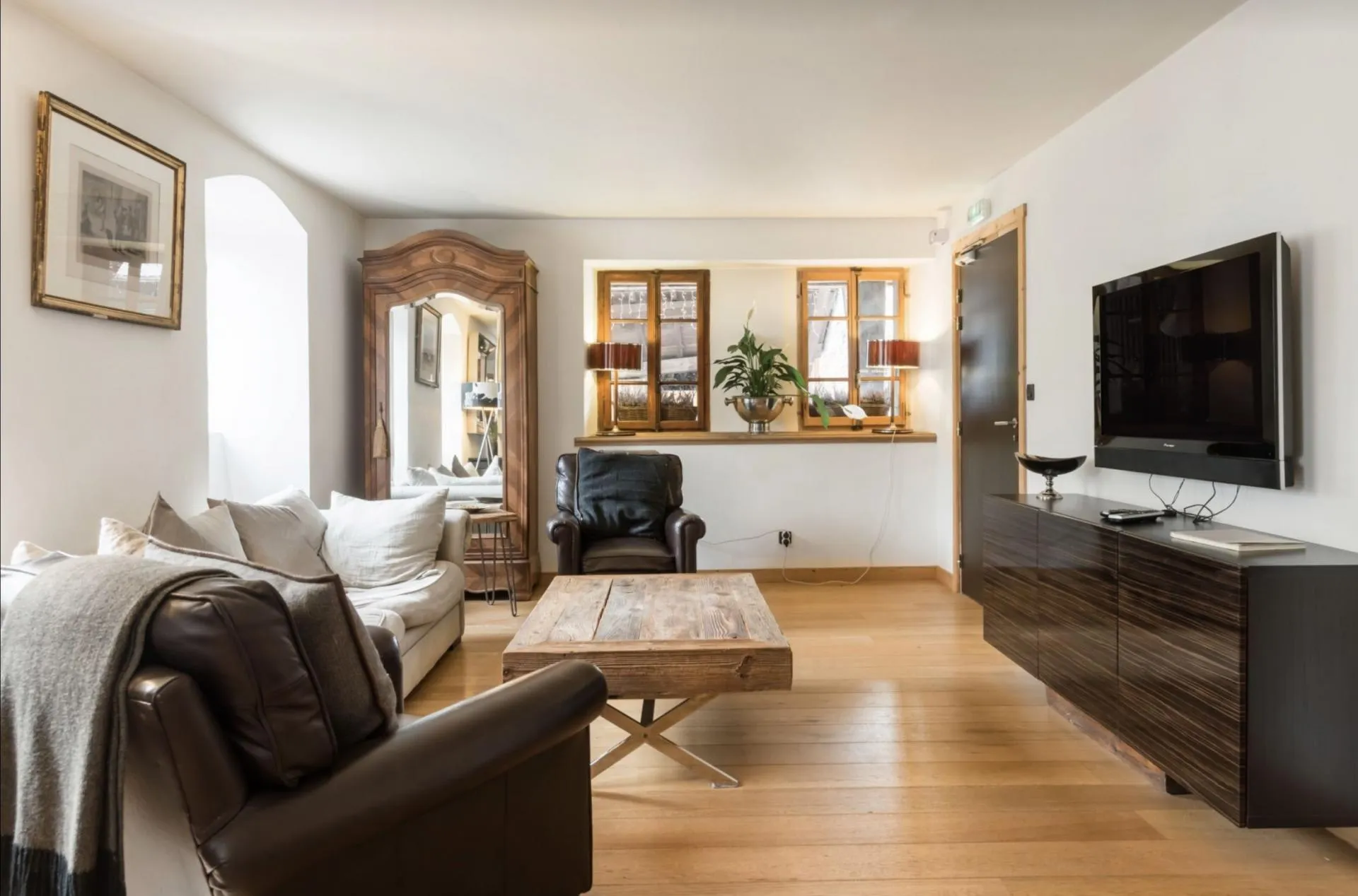 Second sitting area with wall-mounted television and leather armchairs