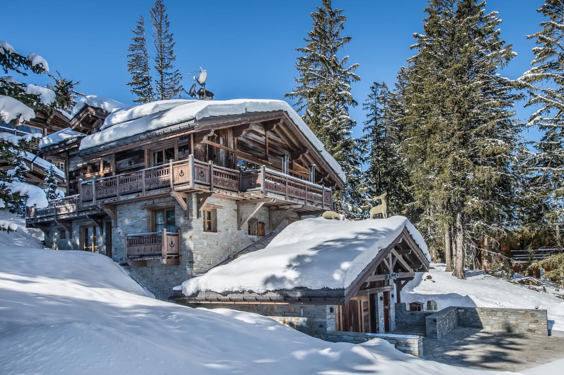 Ski-in chalet exterior with wraparound balconies and private stone patio