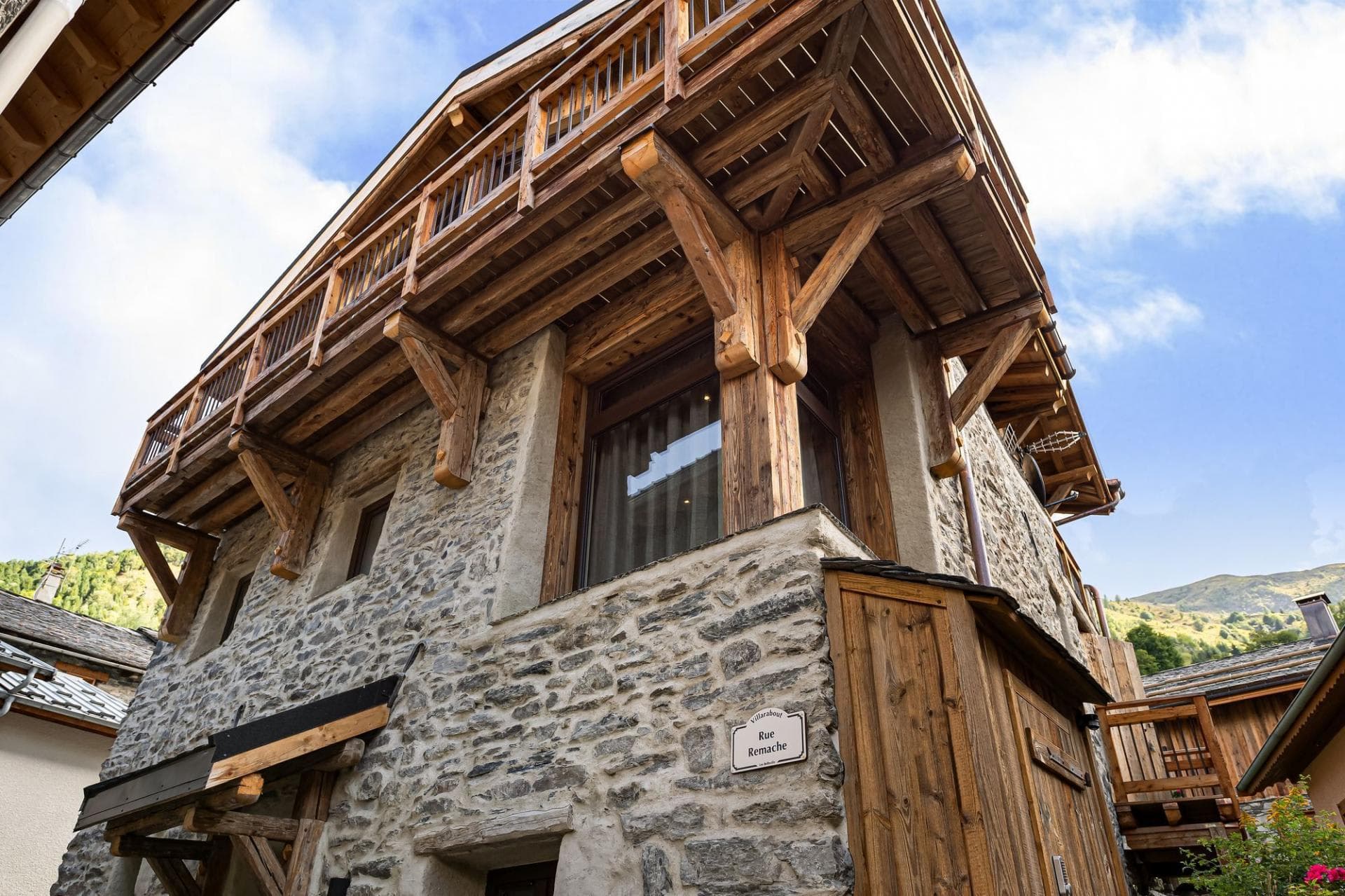 Stone chalet exterior featuring wrap-around timber balconies and mountain views