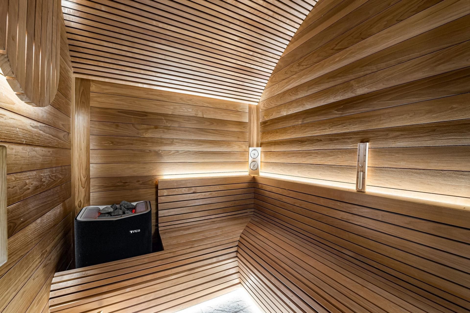 Cedar barrel sauna with electric heater and curved bench seating
