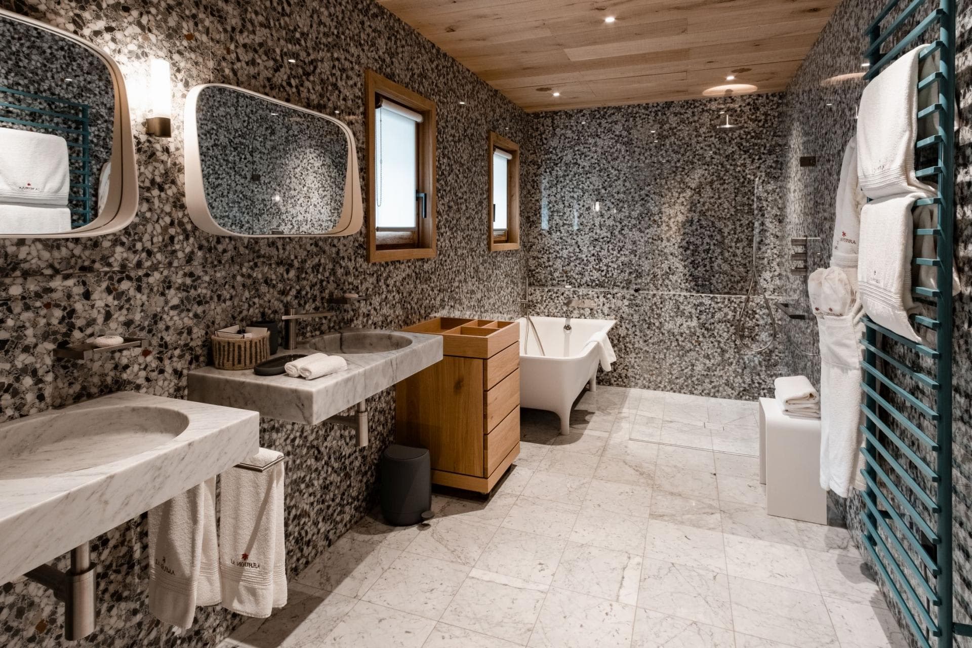 Bathroom with dual marble vanities, soaking tub, and heated towel rack