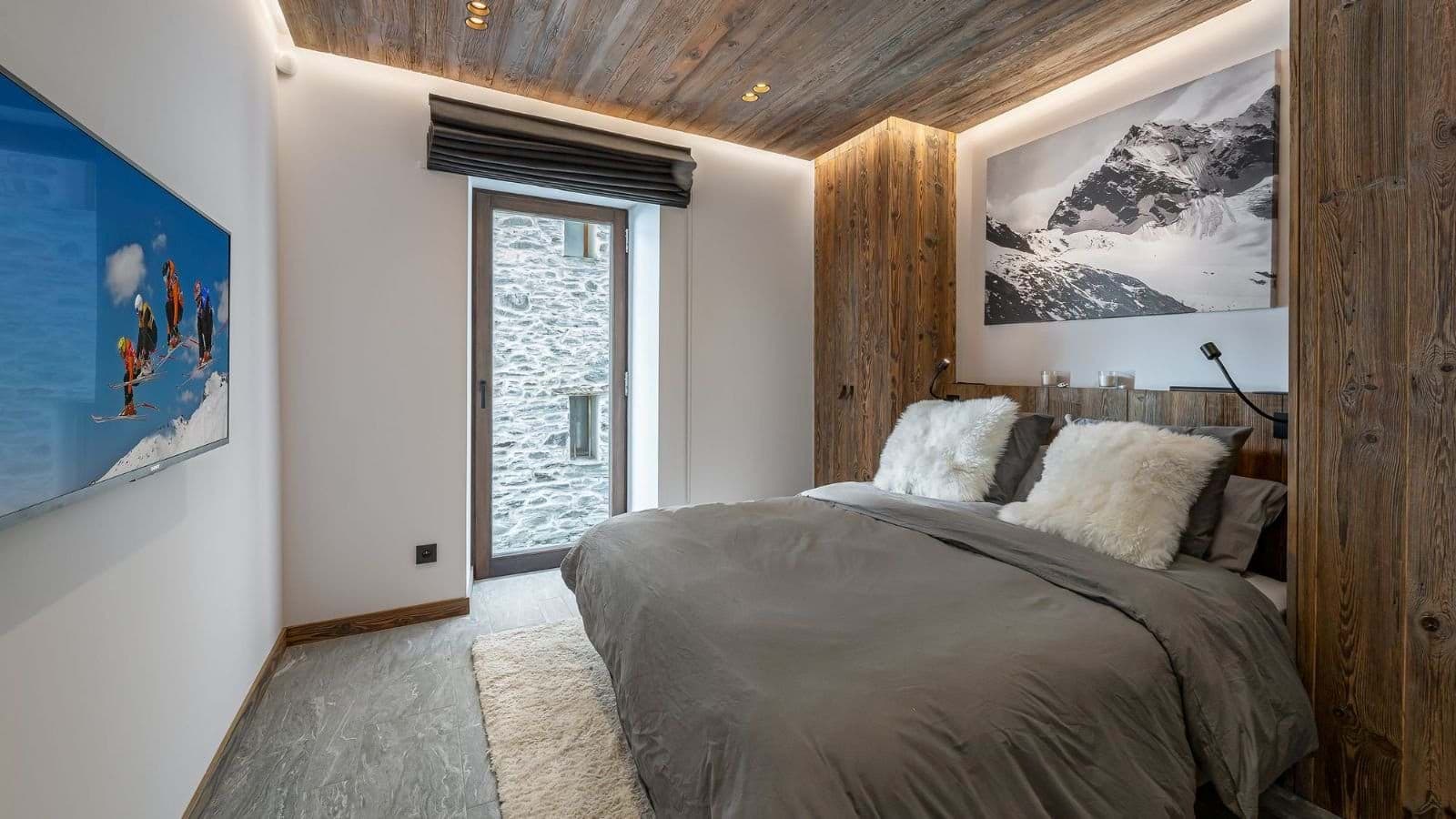 Guest bedroom with queen bed, smart TV, and reclaimed wood ceiling