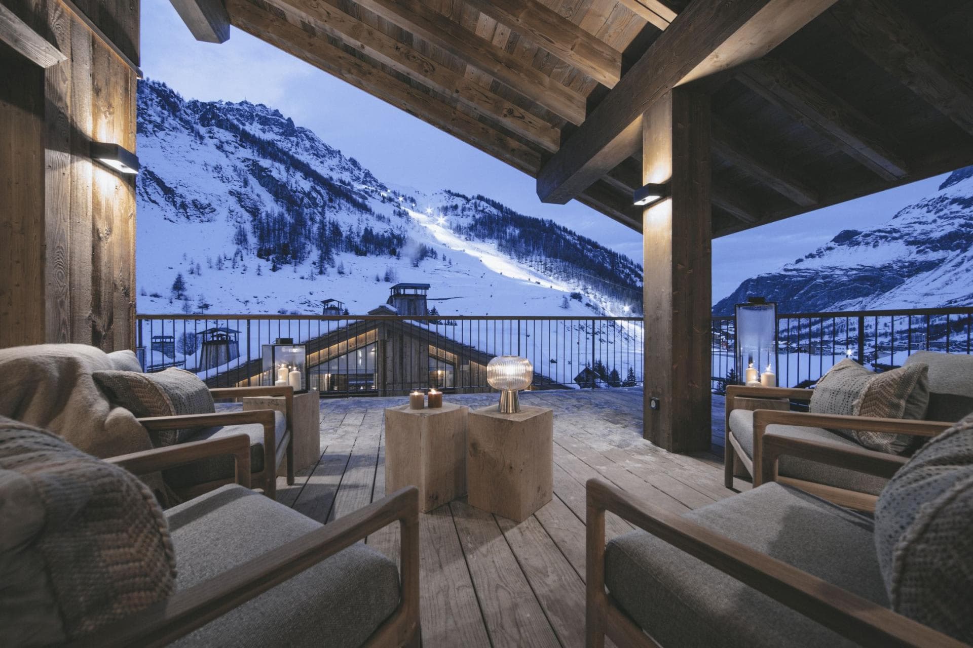 Covered deck with lounge seating and views of illuminated ski slopes