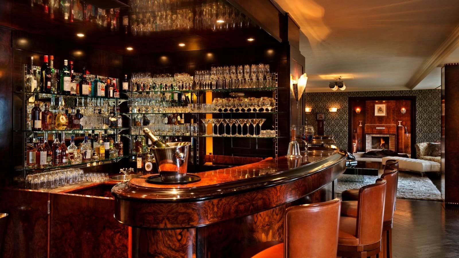 Burled wood wet bar with leather seating and adjacent fireplace lounge