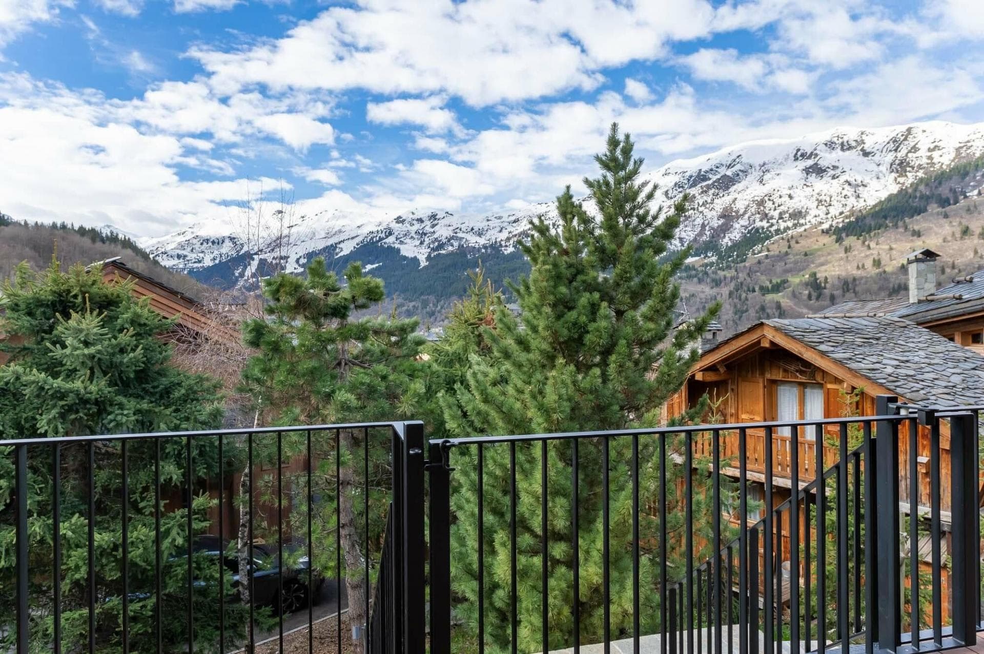 Balcony overlooks snow-capped mountains and neighboring alpine chalets
