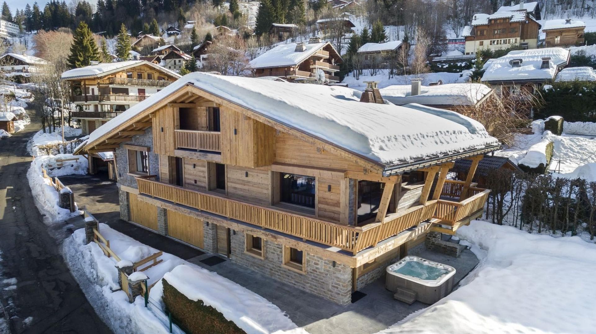 Chalet exterior with ground-floor terrace, hot tub, and two-car garage
