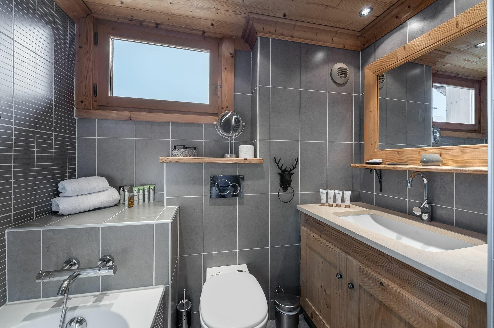 Bathroom with soaking tub, vanity storage, and wall-mounted toilet