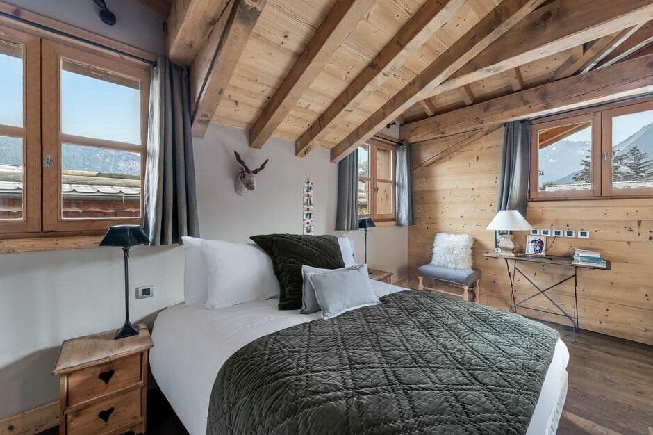 Loft bedroom with exposed beams and mountain views